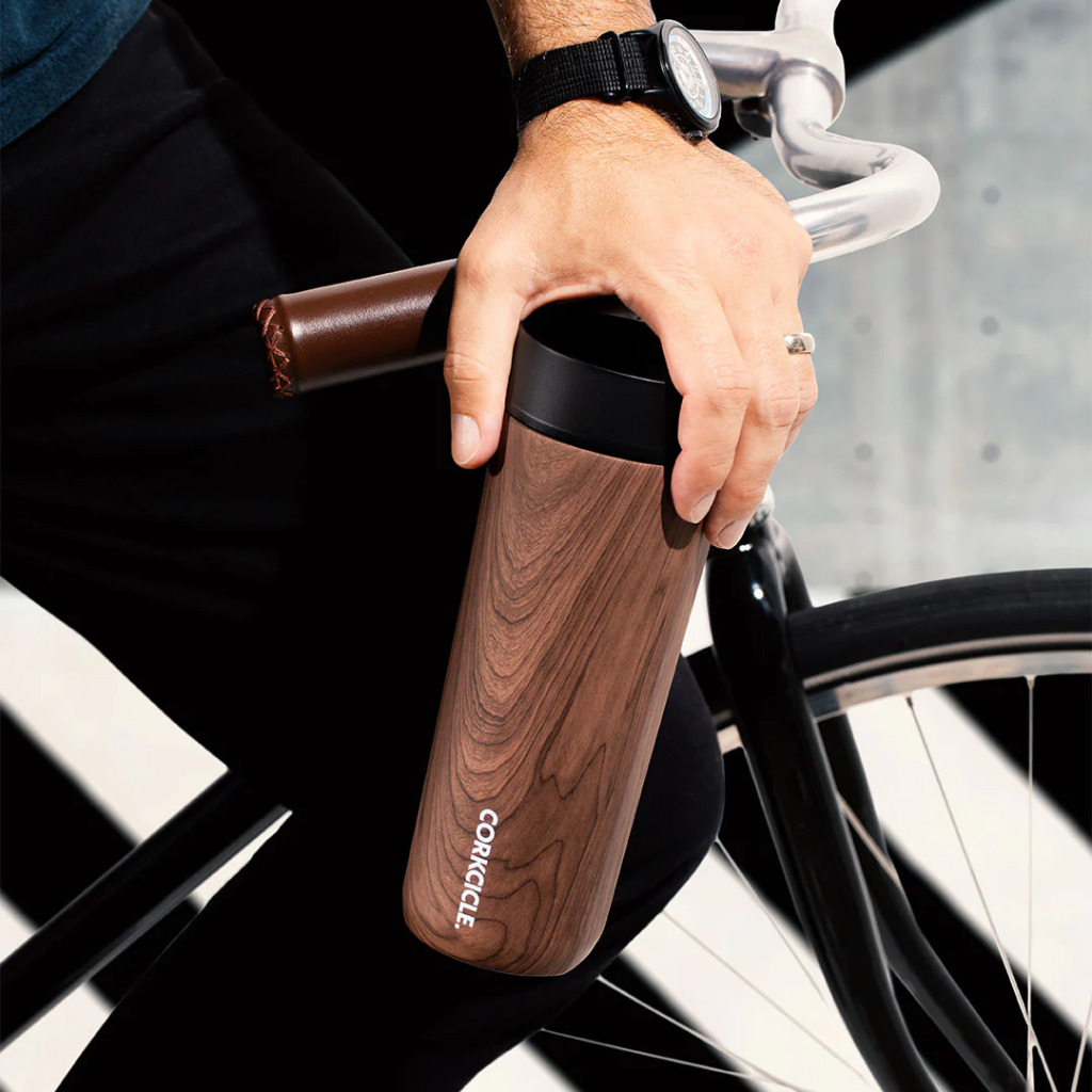 hand holding corkcicle commuter cup in front of bike