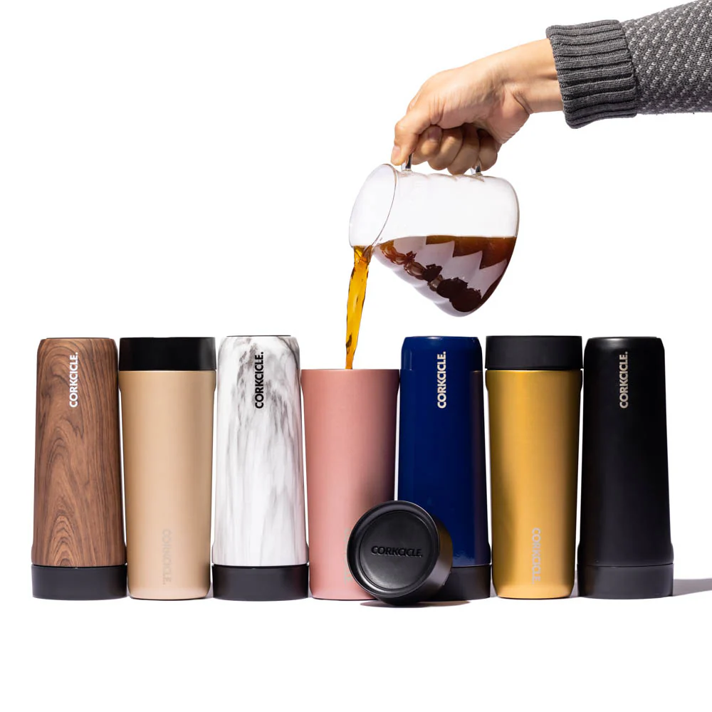 hand pouring coffee into a corkcicle commuter cup next to other corkcicle commuter cups
