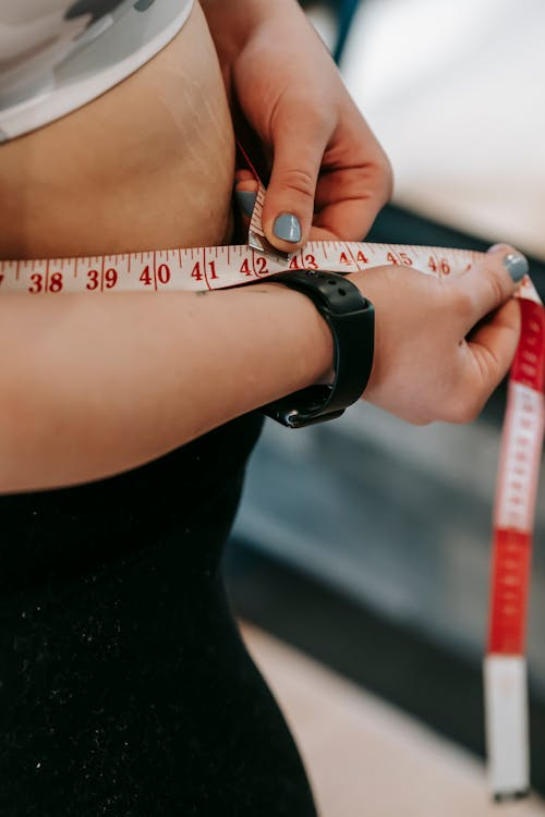 woman measuring her waist with a measuring tape
