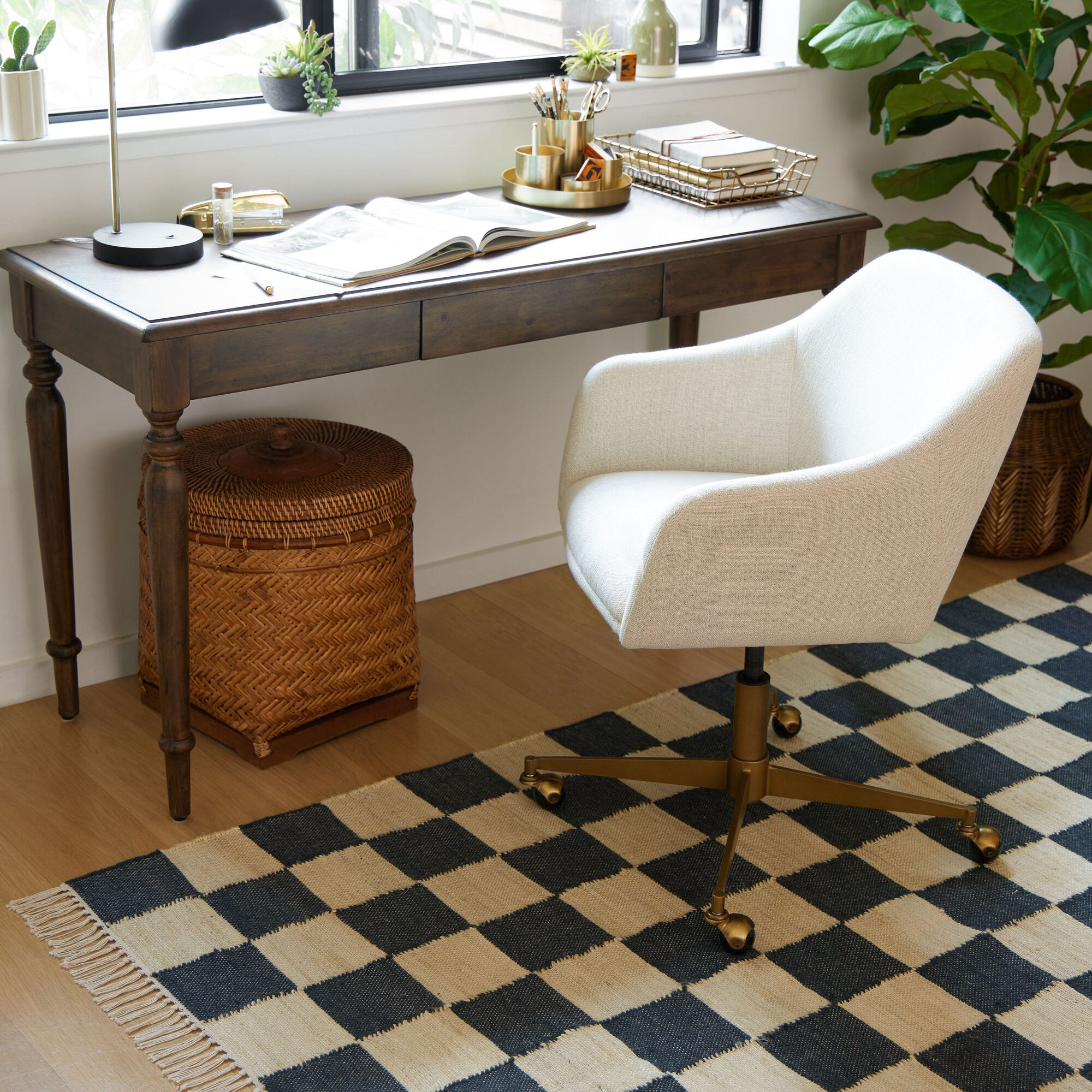 Home office with a wooden desk, white chair, and checkered rug