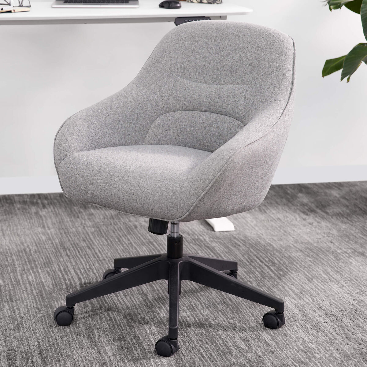 Gray upholstered office chair with wheels on a carpeted floor