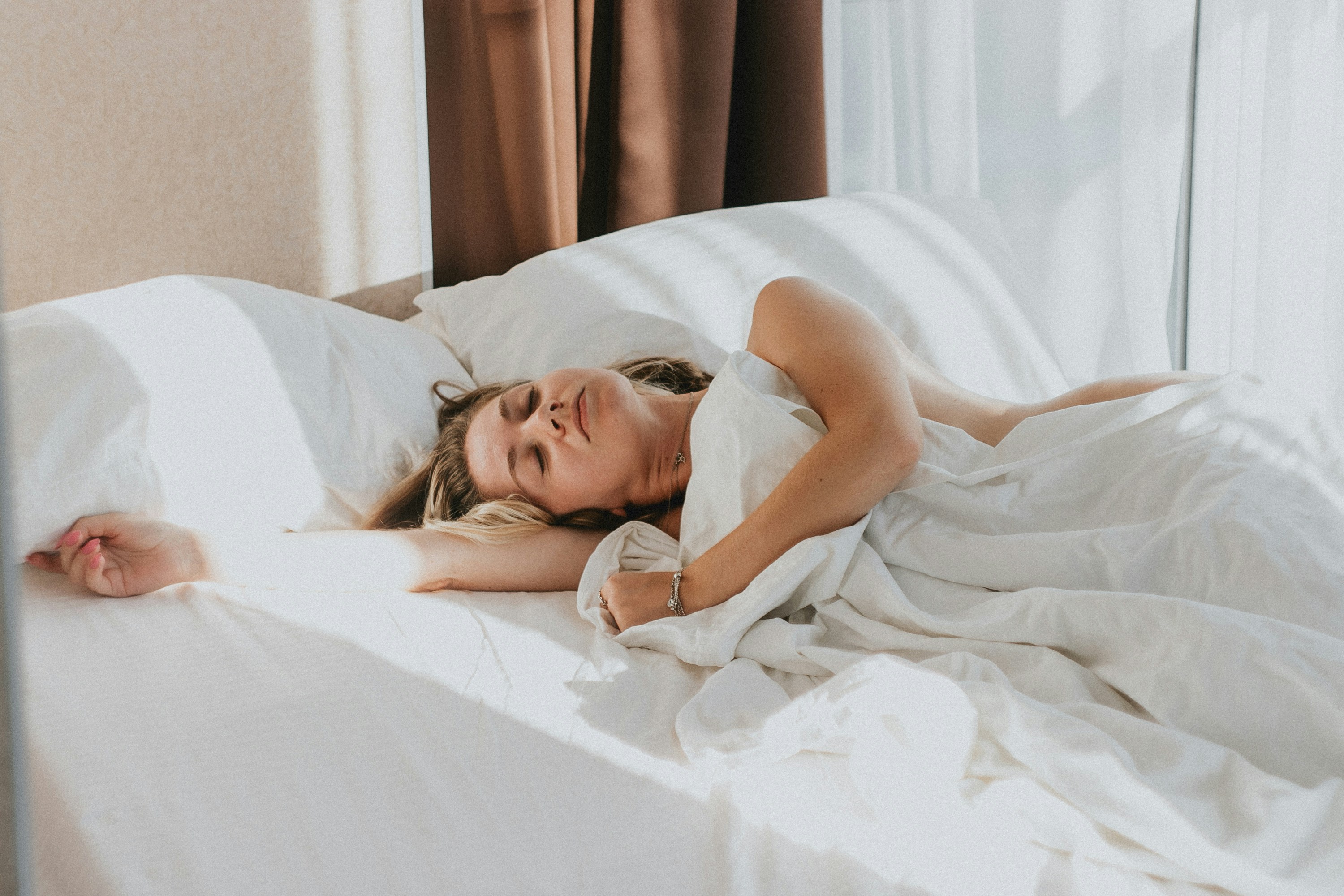Person peacefully sleeping in a sunlit bed