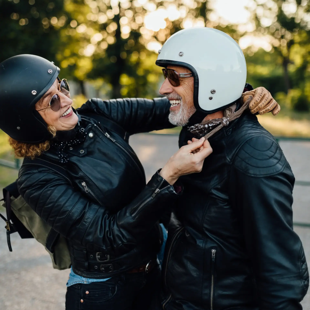 Couple in motorcycle gear sharing a joyful moment outdoors
