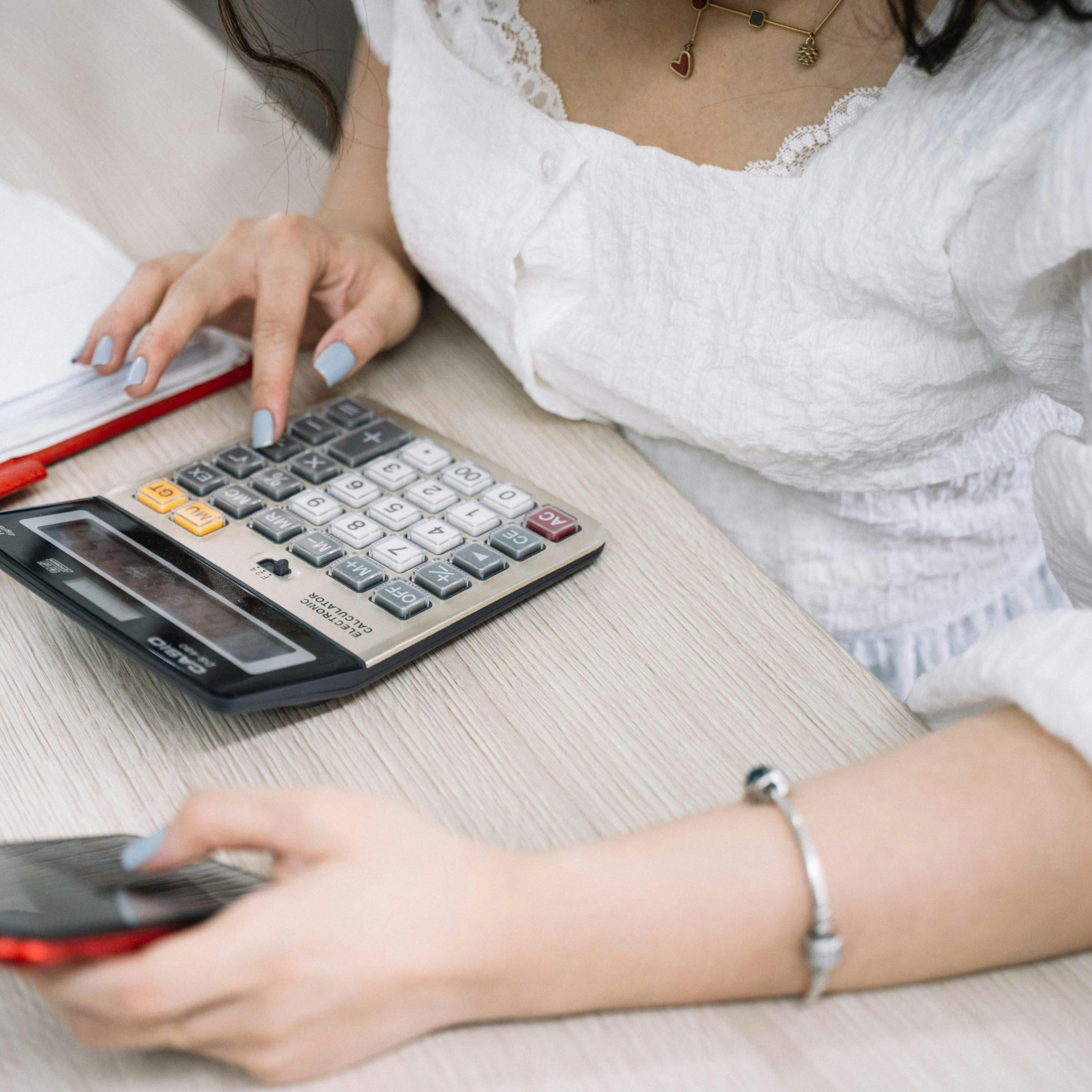A woman comparing costs a calculator while researching GLP-1 providers on her smartphone