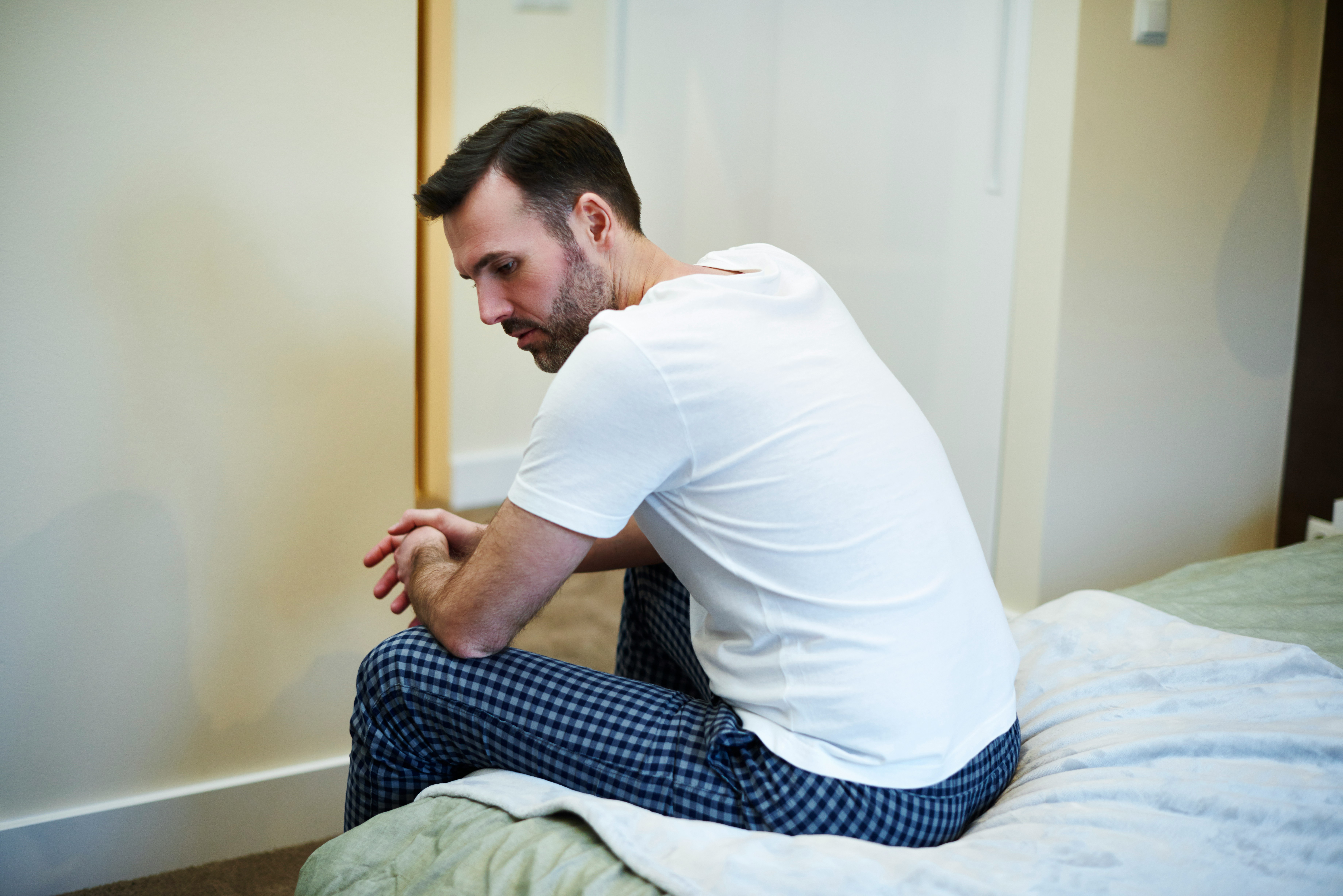 Man sitting on bed in a contemplative pose
