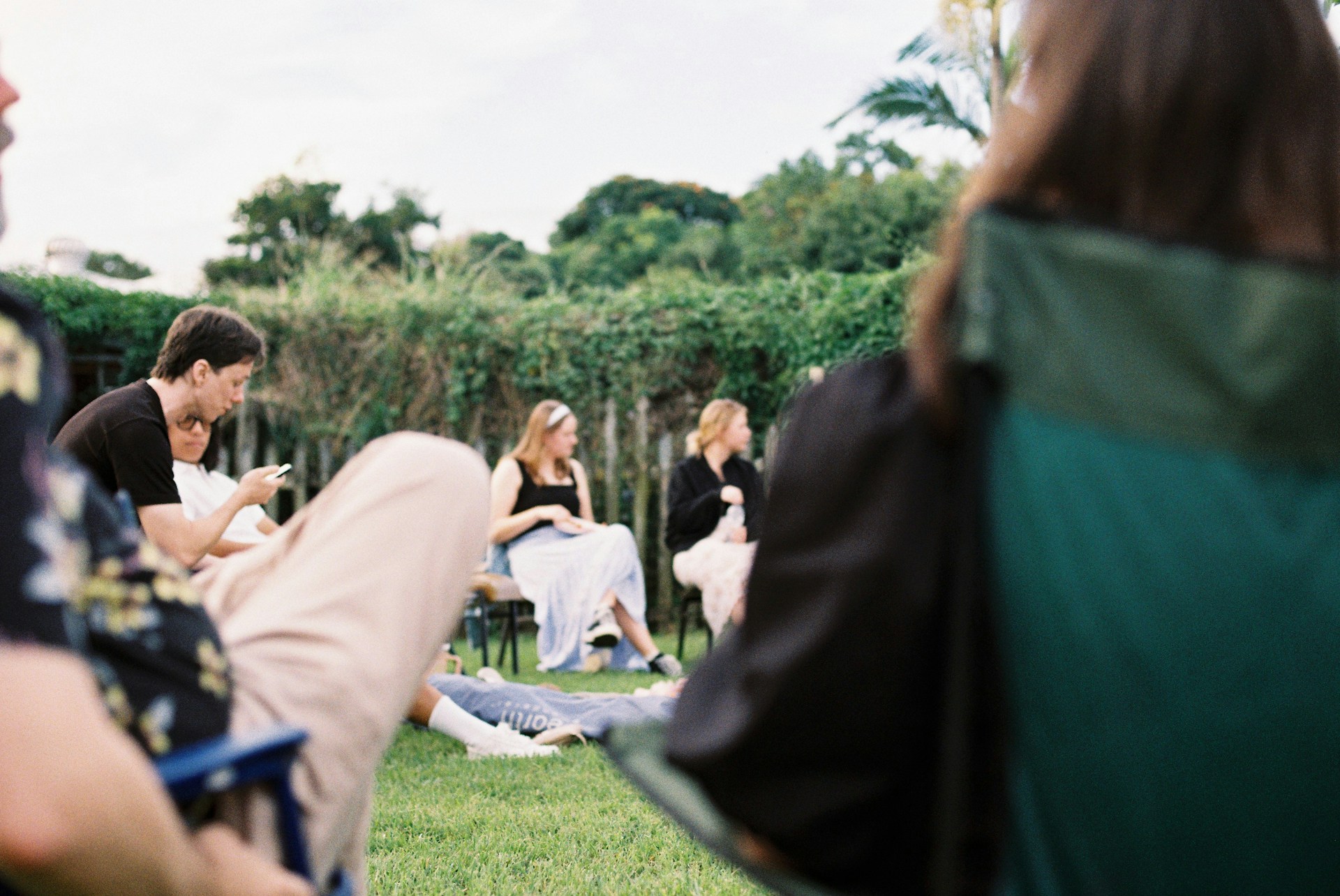 People sitting on chairs and grass in an outdoor setting