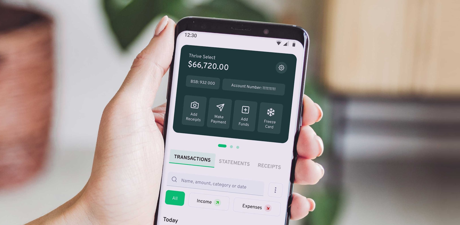Hand holding a smartphone displaying a banking app interface