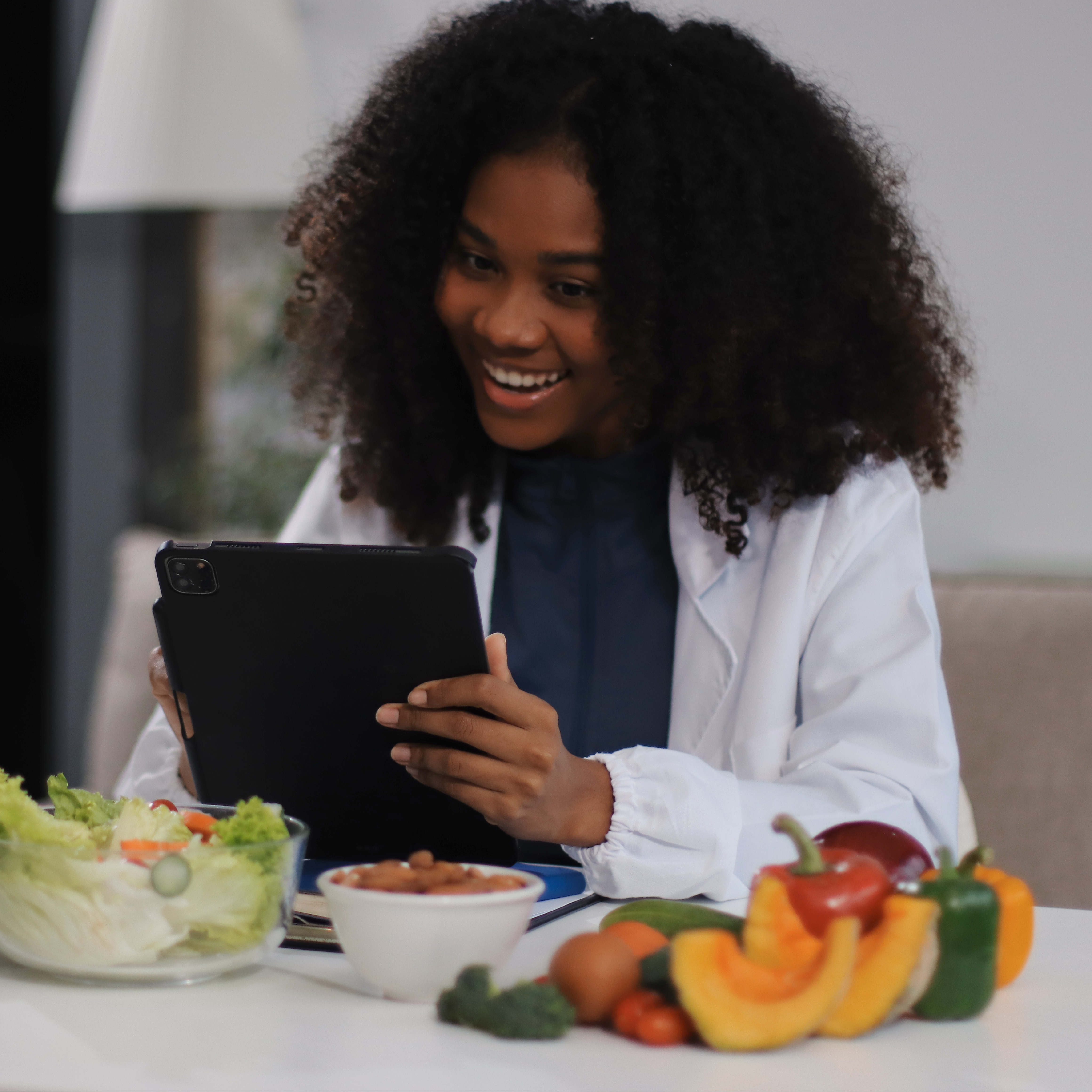 Physician smiling as she provides GLP-1 telehealth treatment via tablet and laptop