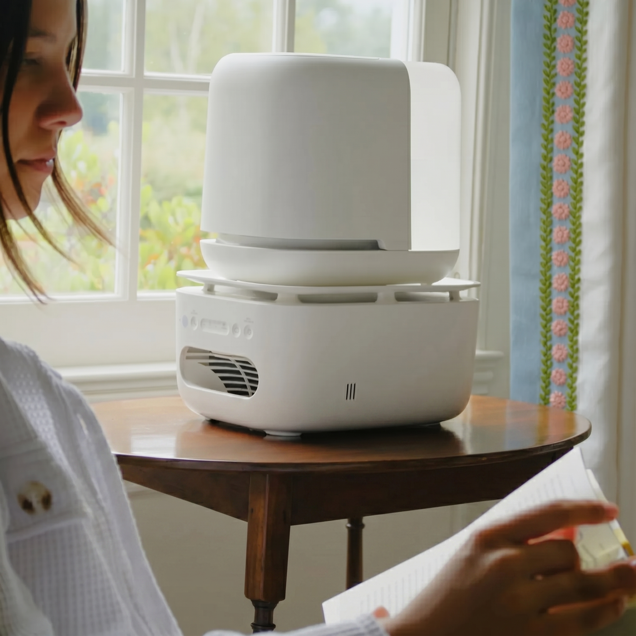 Humidifier on Table by Window Woman reading near a white humidifier on a table