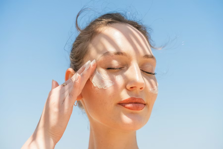 Woman applying sunscreen on her face under sunlight