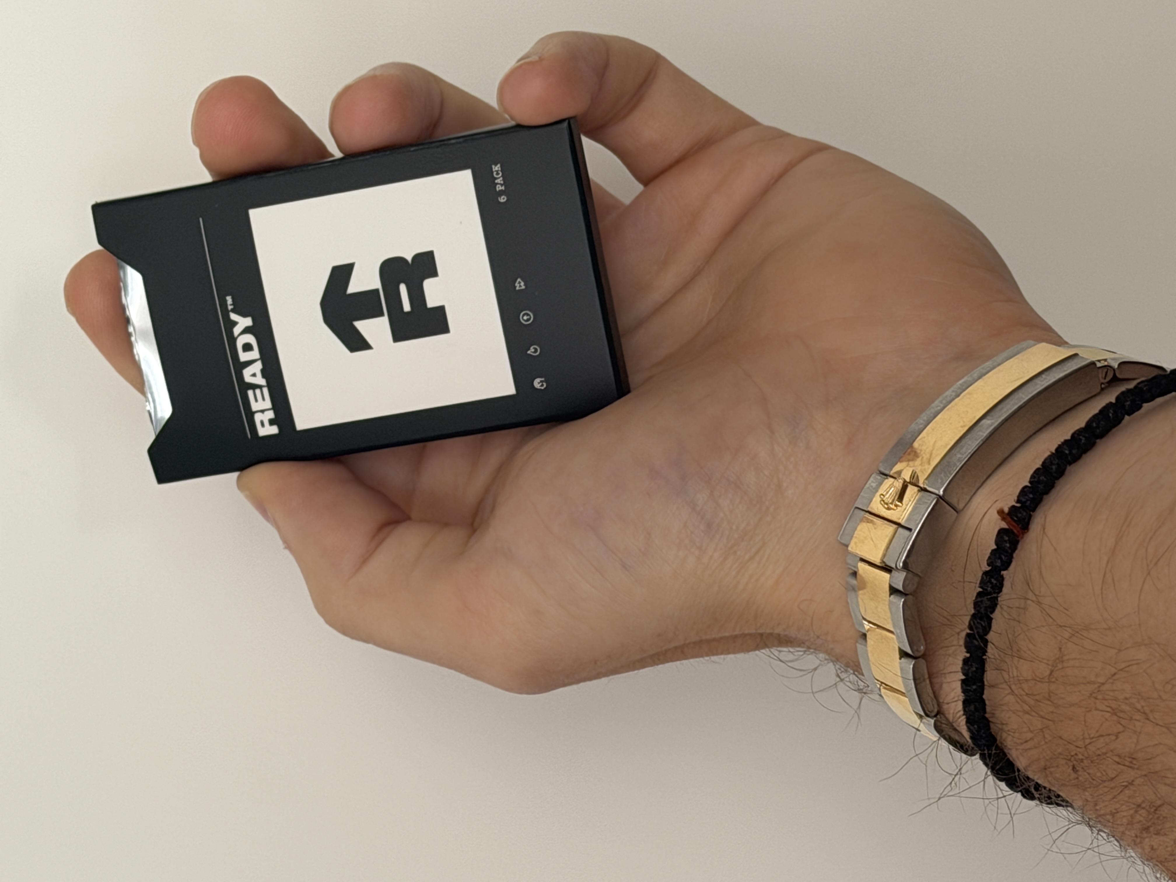 A hand holding a black and white package of Rugiet Ready