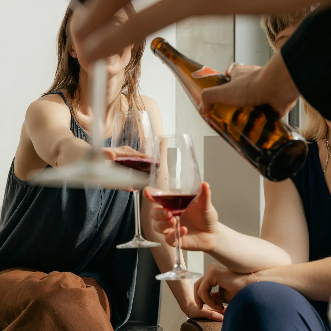 Group of people pouring and holding glasses of red wine
