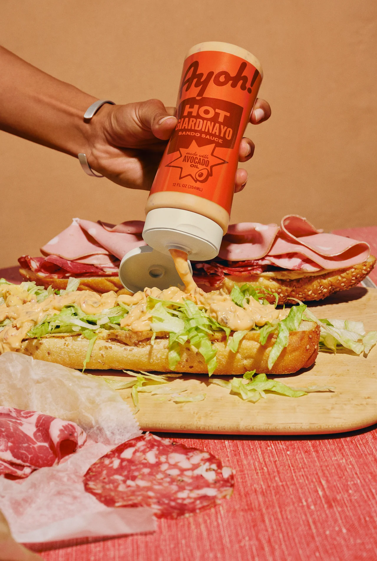 Hand squeezing Ayoh Hot Giardinayo onto a sandwich