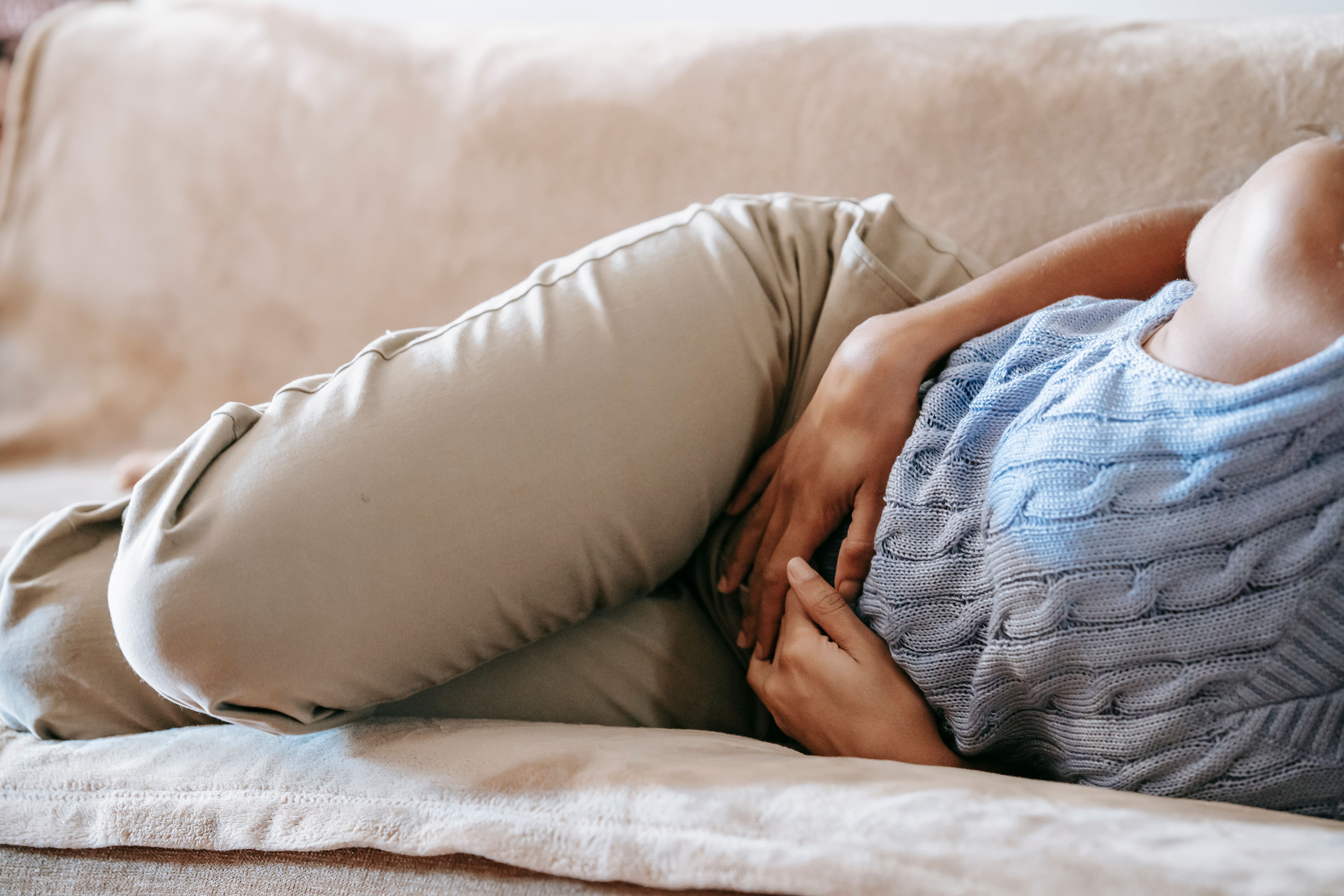 Person lying on a couch holding their stomach