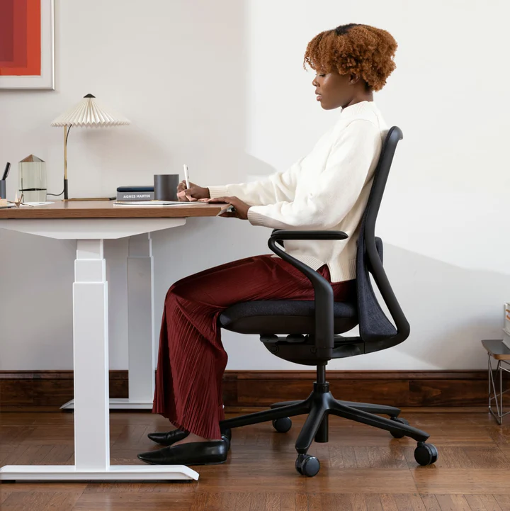Woman sitting at a desk in the Verve Chair writing in a notebook
