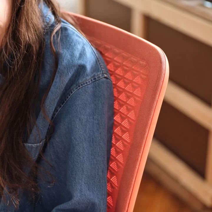 Person sitting on a Coral Verve Chair wearing a denim shirt