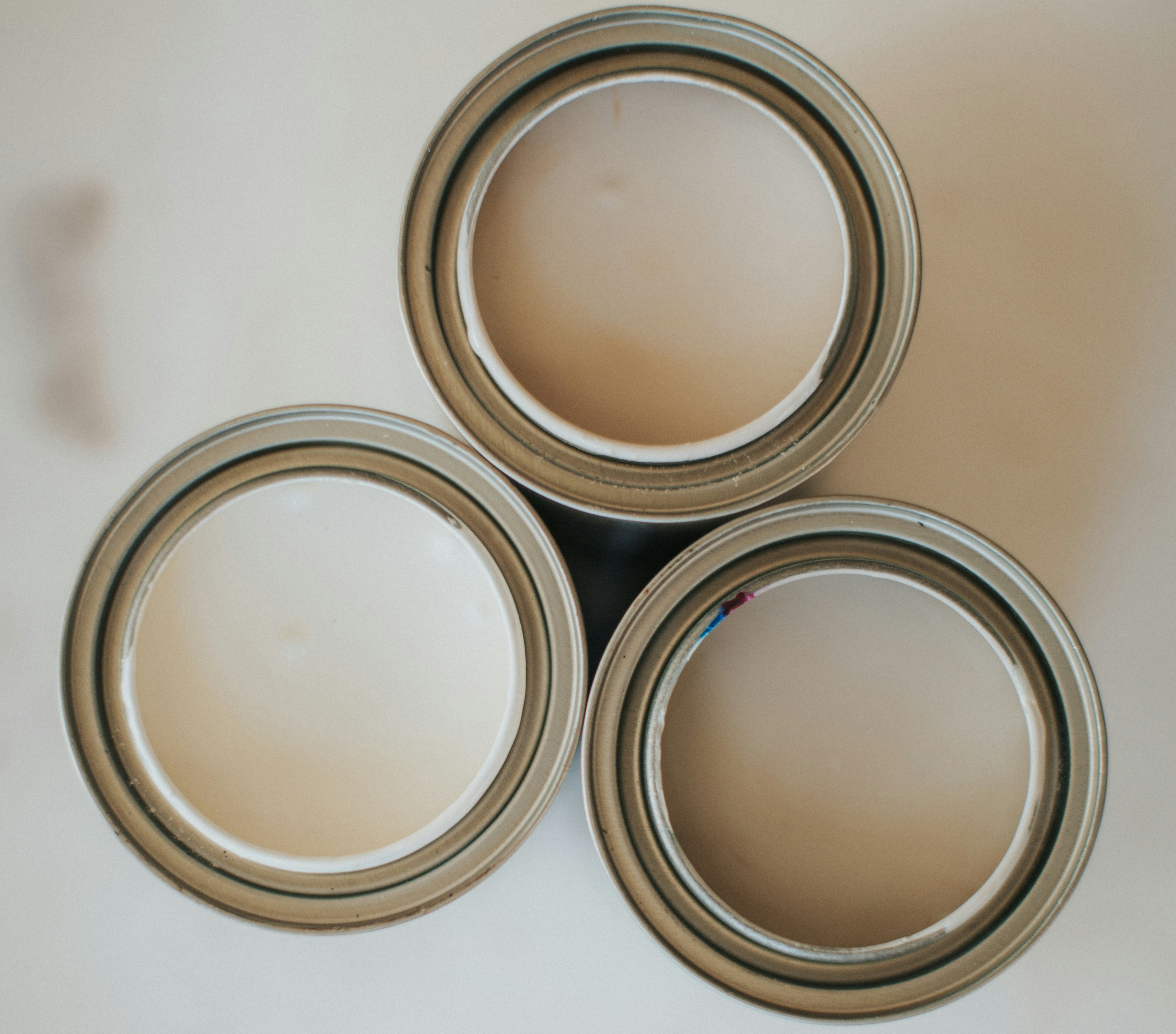 Three open cans of beige paint