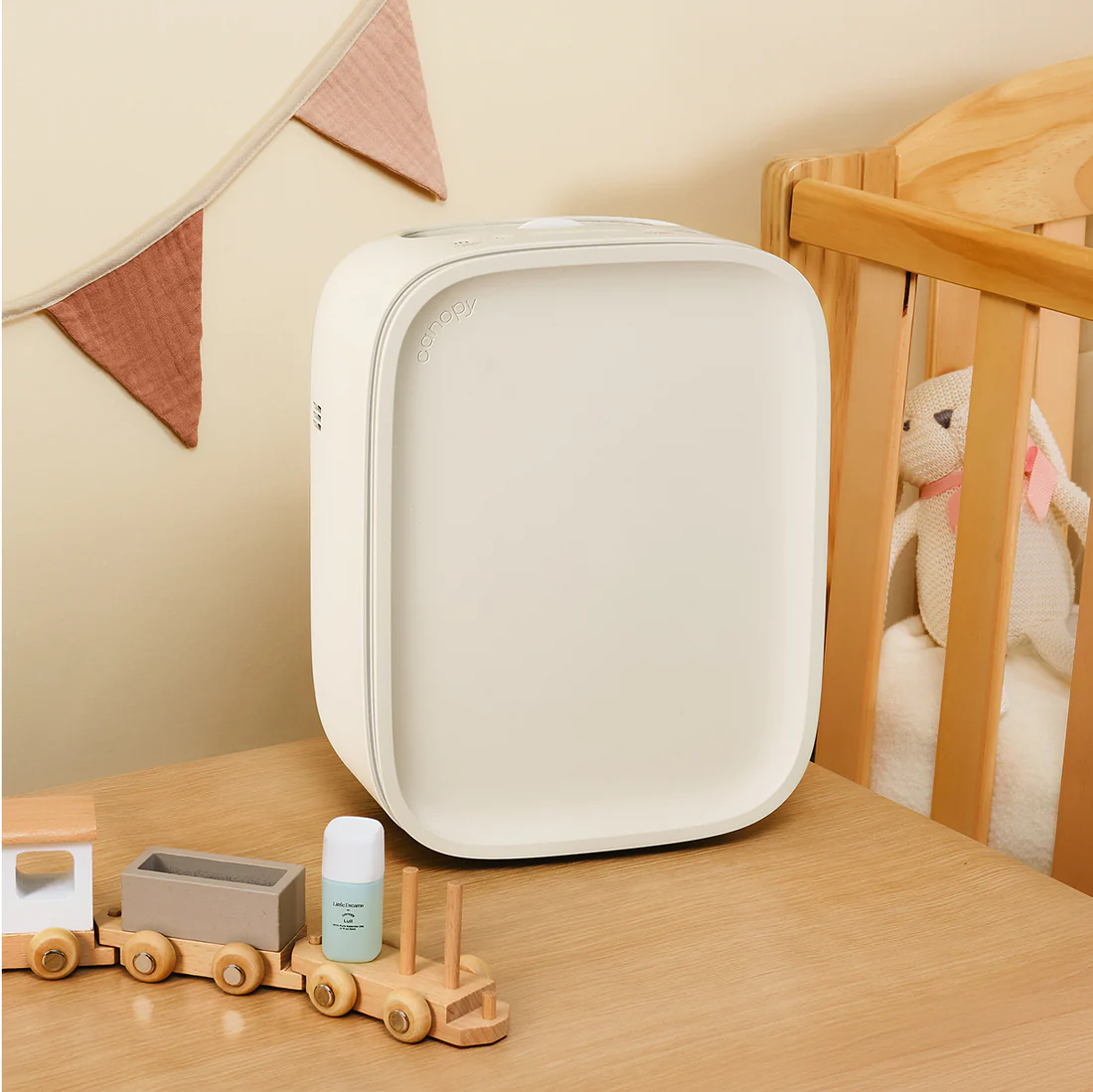 The Canopy Nursery Air Purifier perched on a table beside a crib