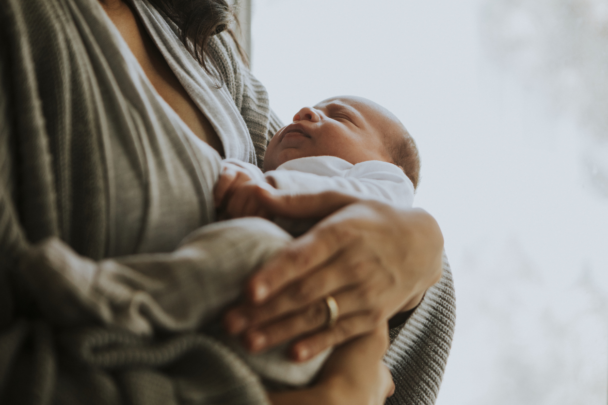 Woman holding her baby near a window