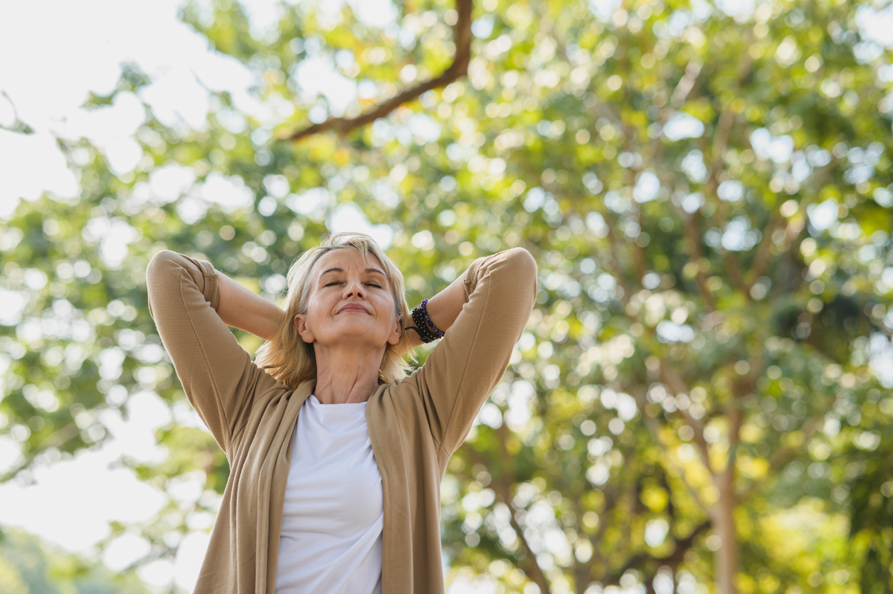Woman taking a walk outside, smiling near the trees