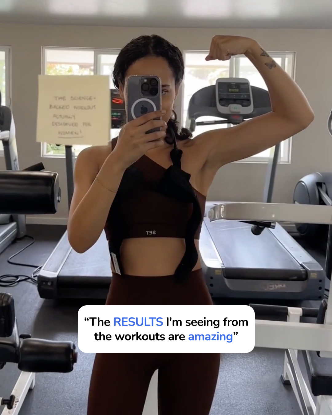 Woman flexing her muscles in the mirror of her home gym