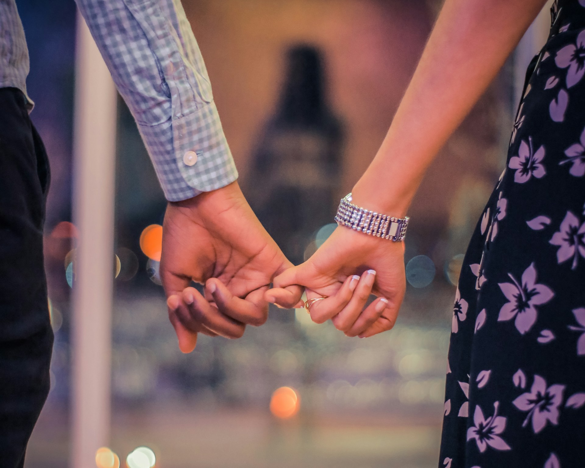 Couple holding hands with a blurred city background