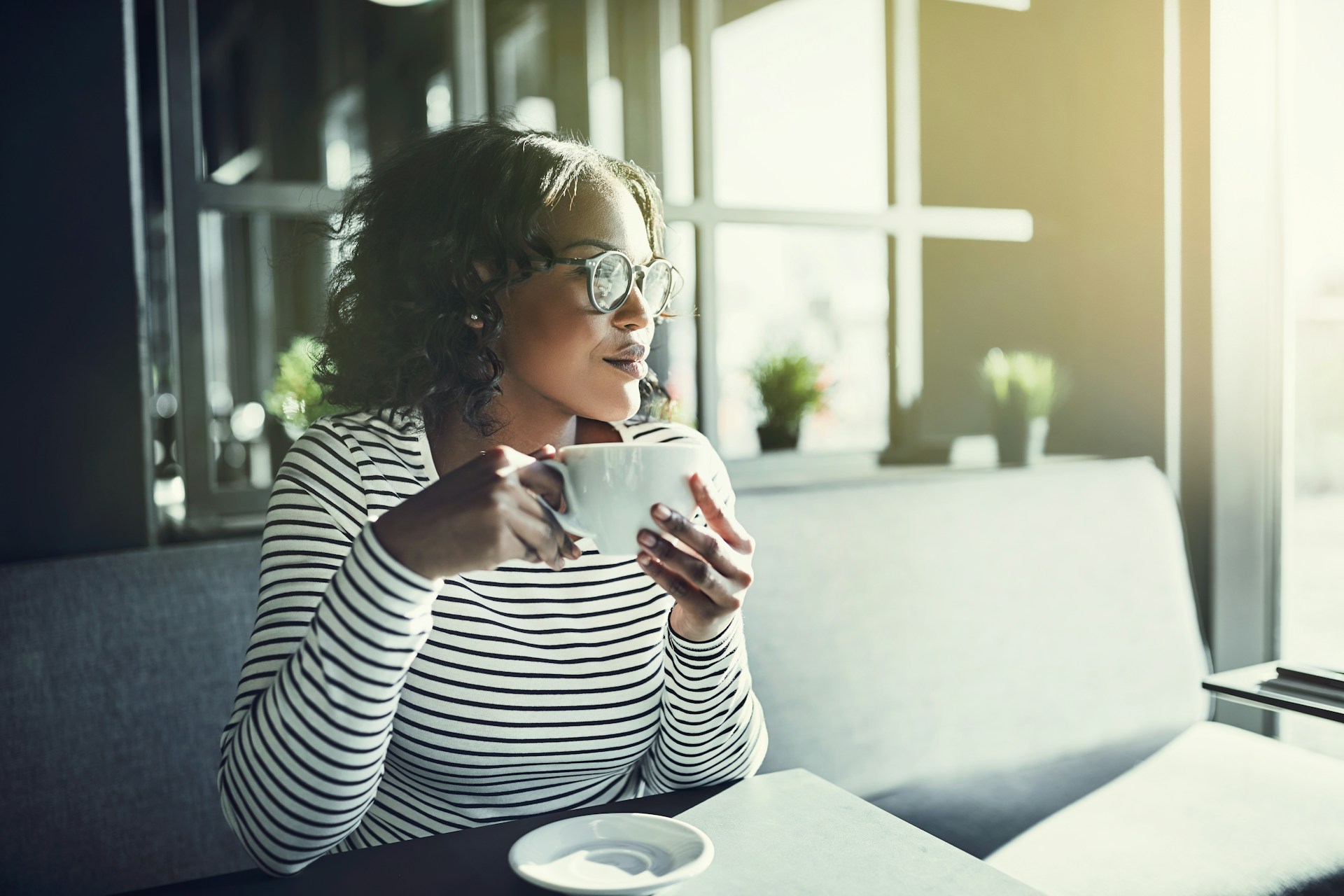 A woman holding a coffee cup and looking out of the window in a cafe