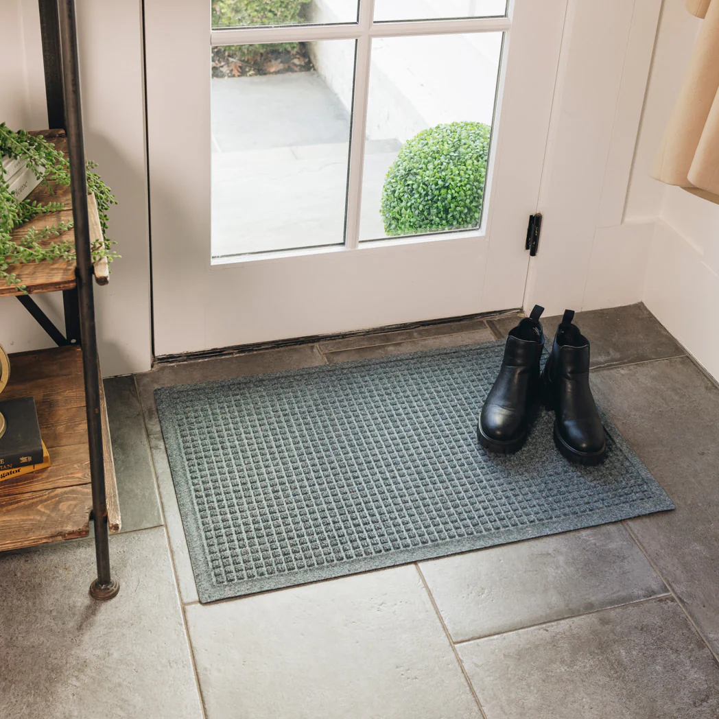 Boots on top of a WaterHog Squares Doormat near a door