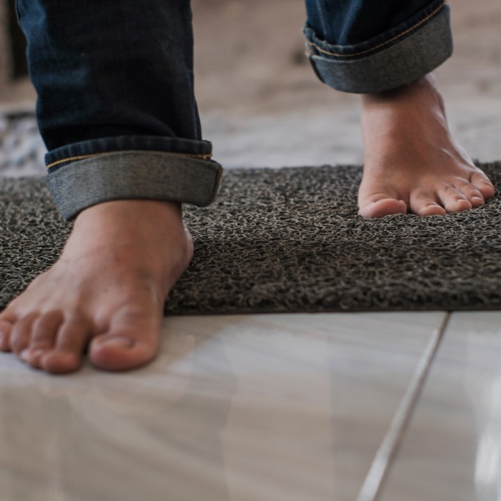 Close up of feet walking over a doormat