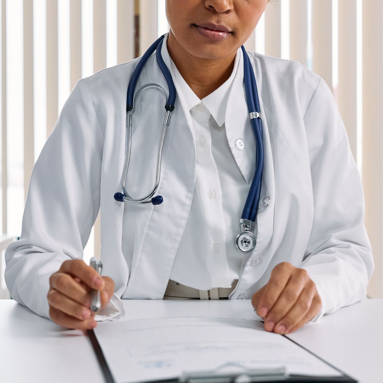 A doctor in a white coat with a stethoscope reviews a patient's chart