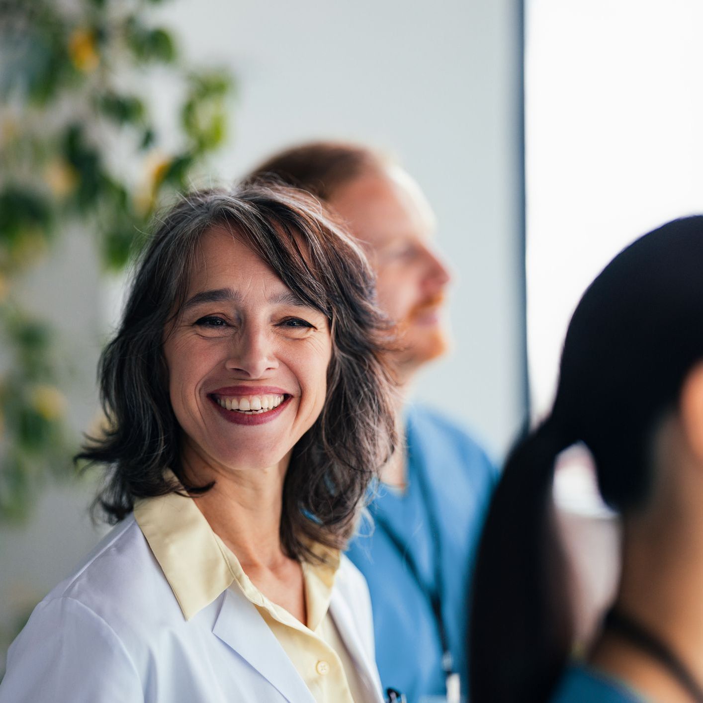 Smiling healthcare professional stands with colleagues in a bright room
