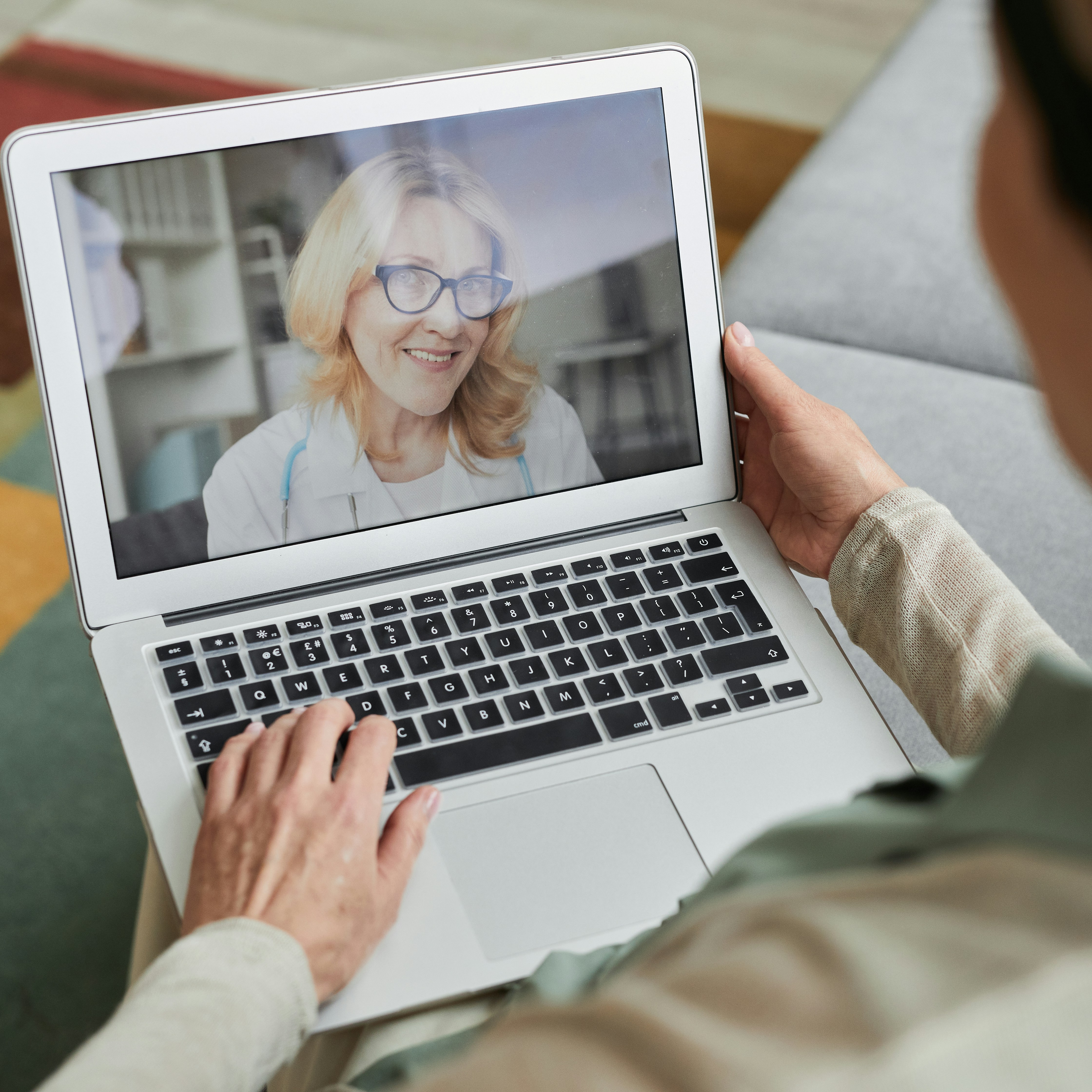 A person participates in a virtual consultation with a healthcare provider on a laptop
