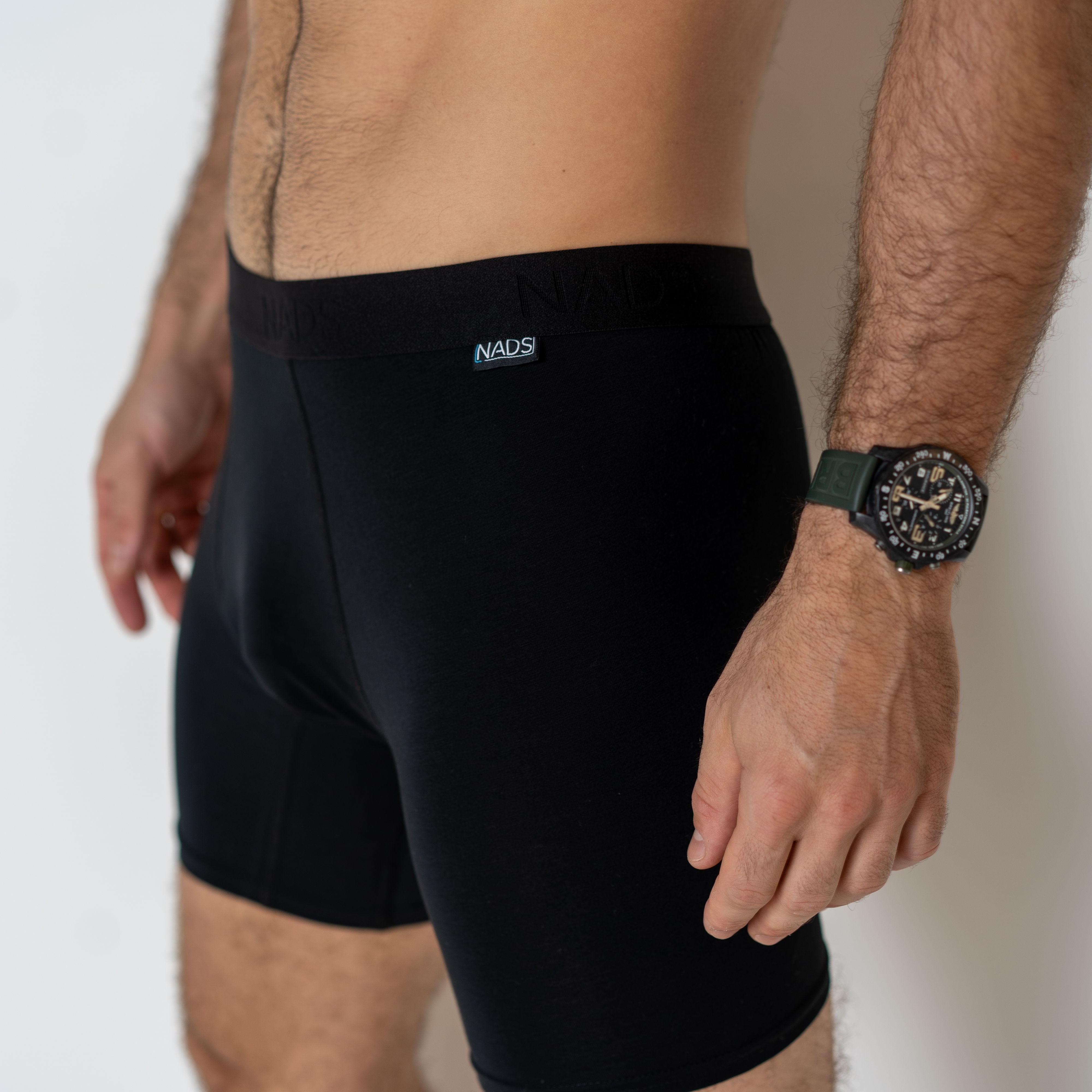NADS Compression Boxer Briefs Man wearing NADS Compression Boxer Briefs and a watch stands against a light background