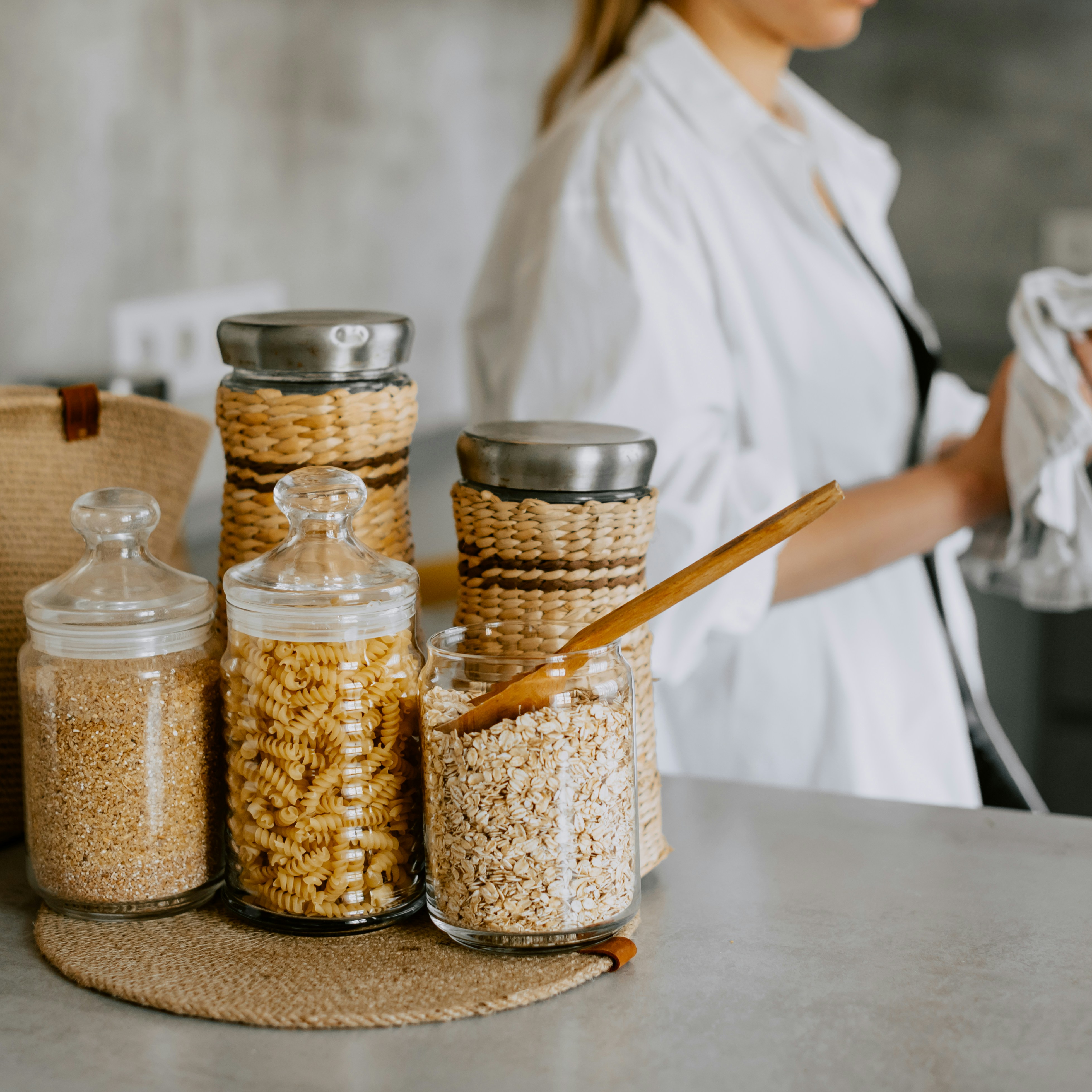 Glass jars filled with pantry staples like pasta and grains sit on a kitchen counter