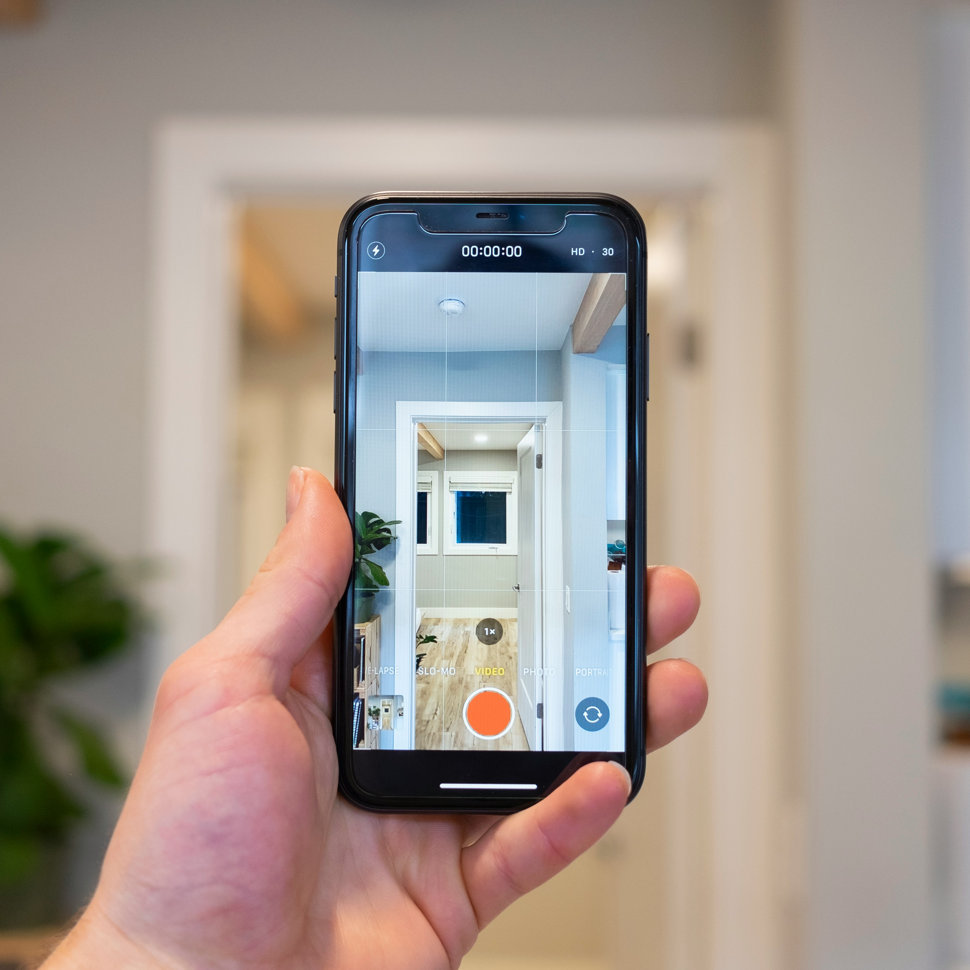 Recording Hallway with Smartphone Person holds a smartphone showing a video of a hallway with wooden floors