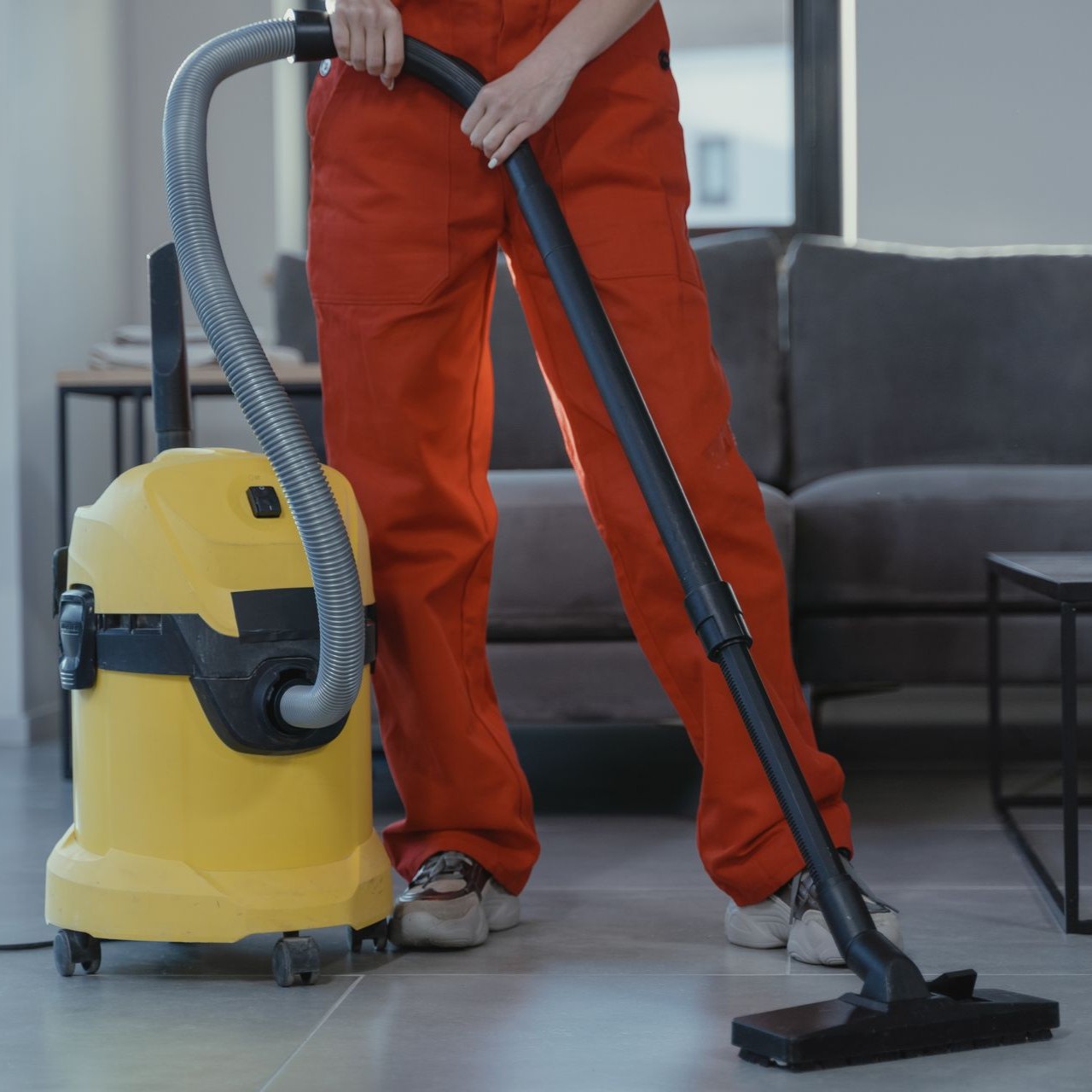 Vacuuming Tiled Floor Person in red overalls vacuuming a tiled floor with a yellow vacuum cleaner