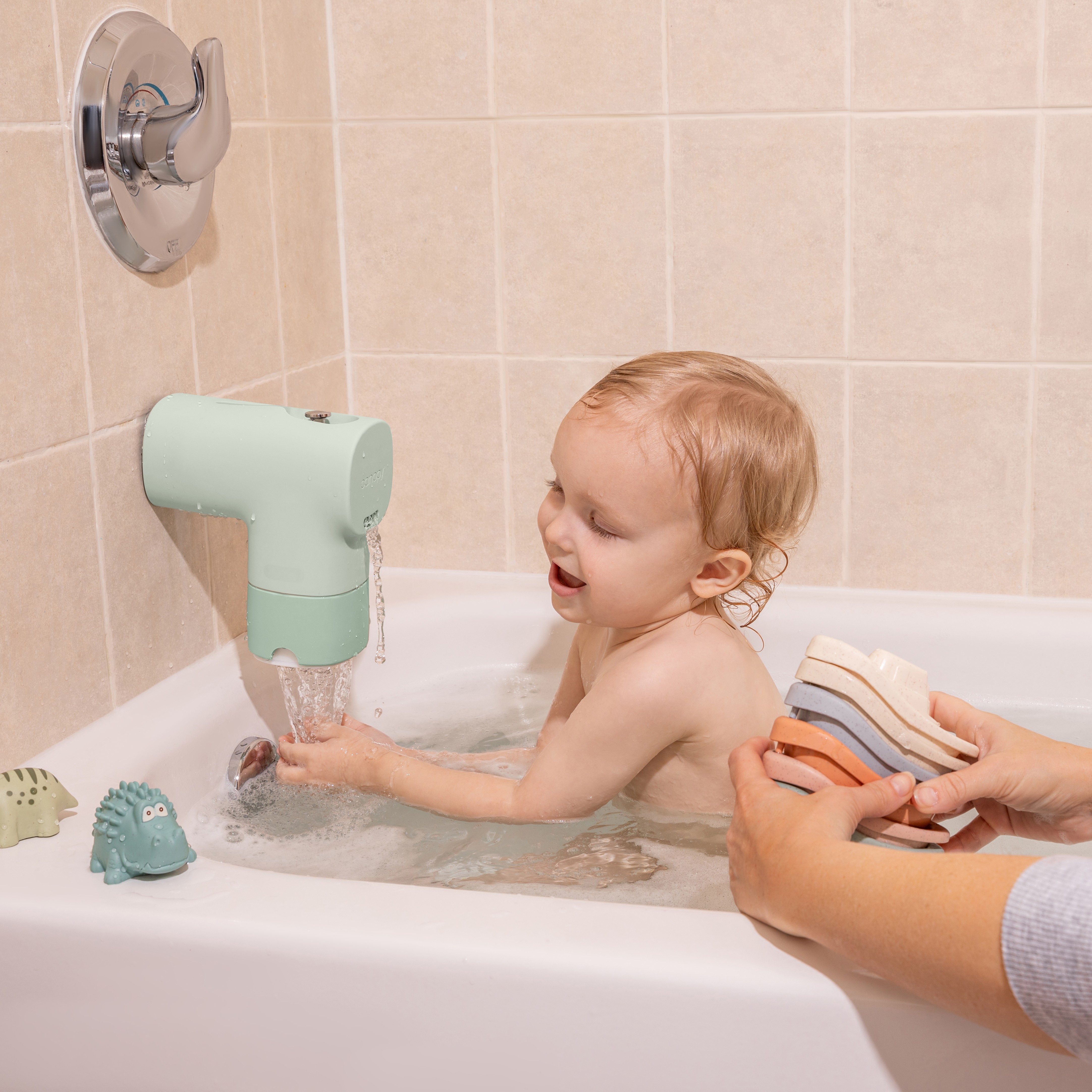 A baby enjoys a bath with a Canopy Baby Bath Tub Filter attached to the faucet