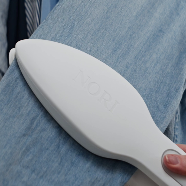 A Nori Press Steam Iron is used on a jean shirt