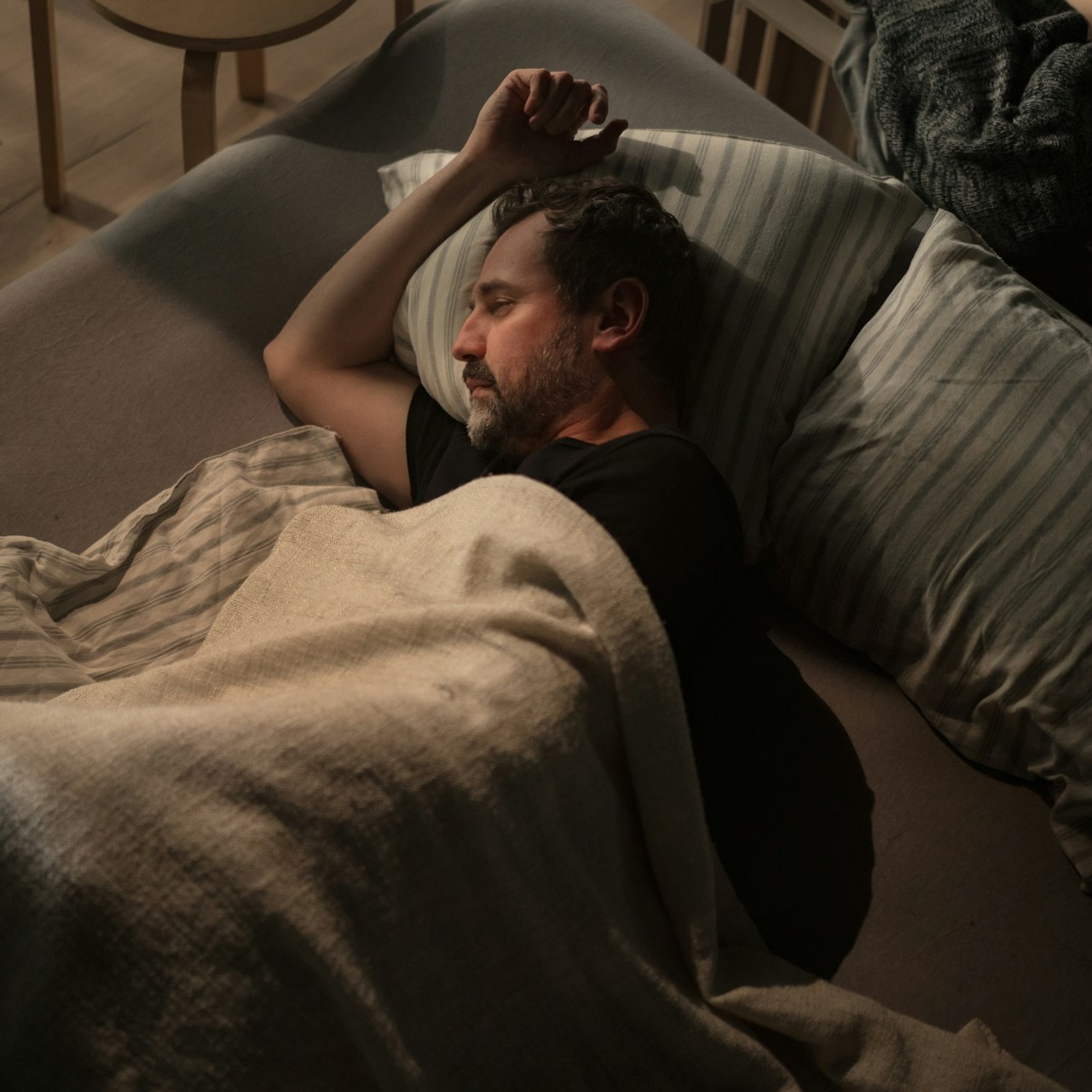 Mature man tries to sleep alone in bed, suffering from insomnia