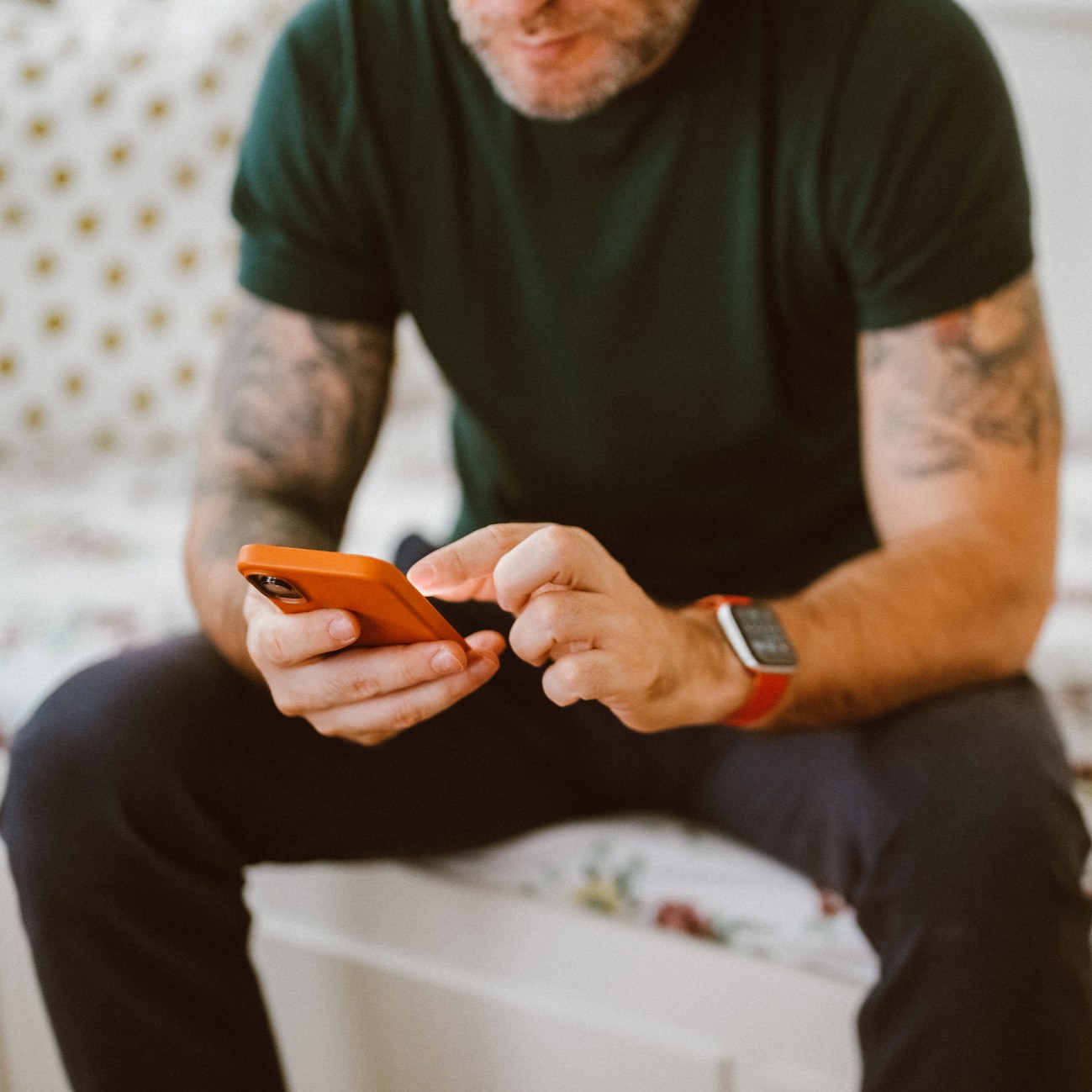 Man with tattoos uses a smartphone while sitting indoors