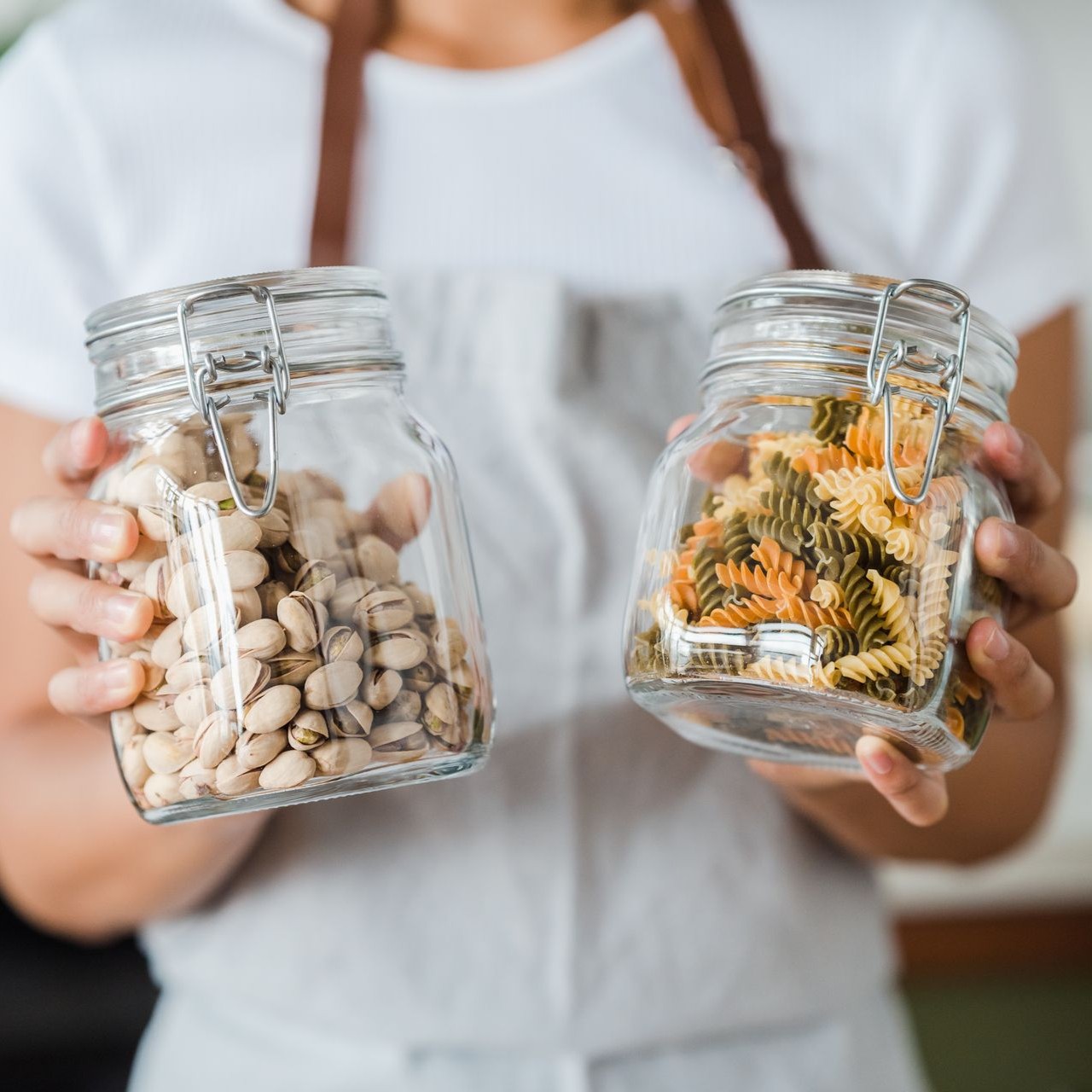 Jars of Pistachios and Pasta Person holds jars of pistachios and colorful pasta in a kitchen