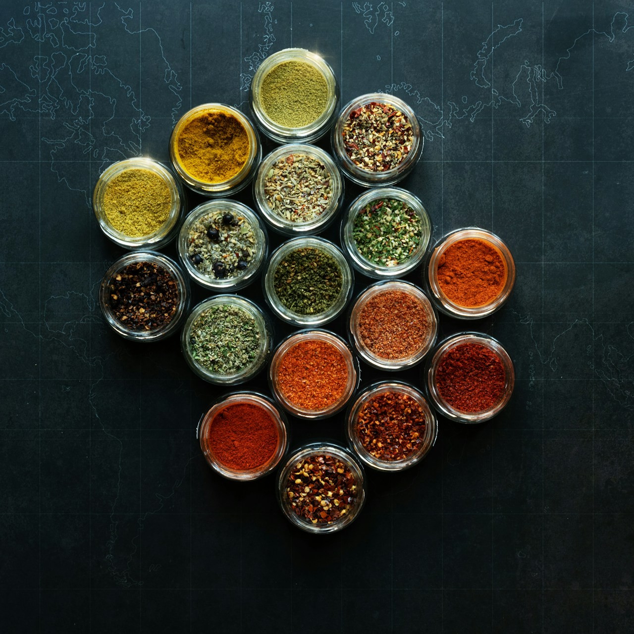 Assorted Spices in Glass Jars Various spices in small glass jars are arranged on a dark surface