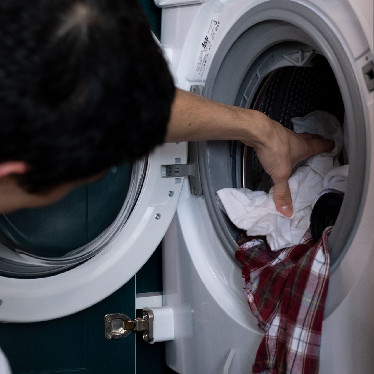 Loading Laundry into Washing Machine Person loads laundry into a front-loading washing machine