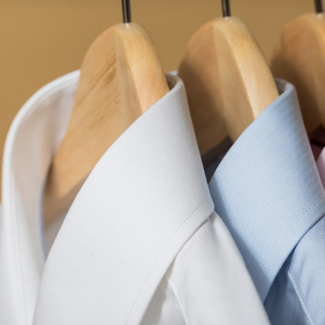 Dress Shirts on Hangers Three dress shirts in white, blue, and pink hang on wooden hangers