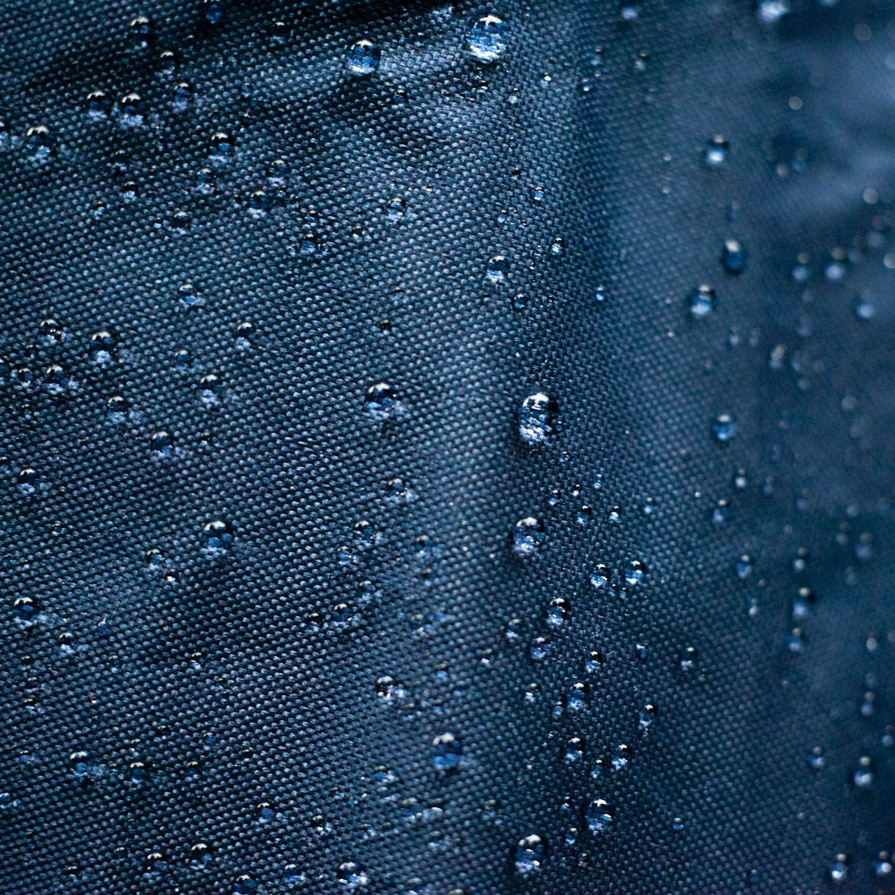 Water-Repellent Fabric Close-Up Water droplets bead on a dark, textured fabric surface