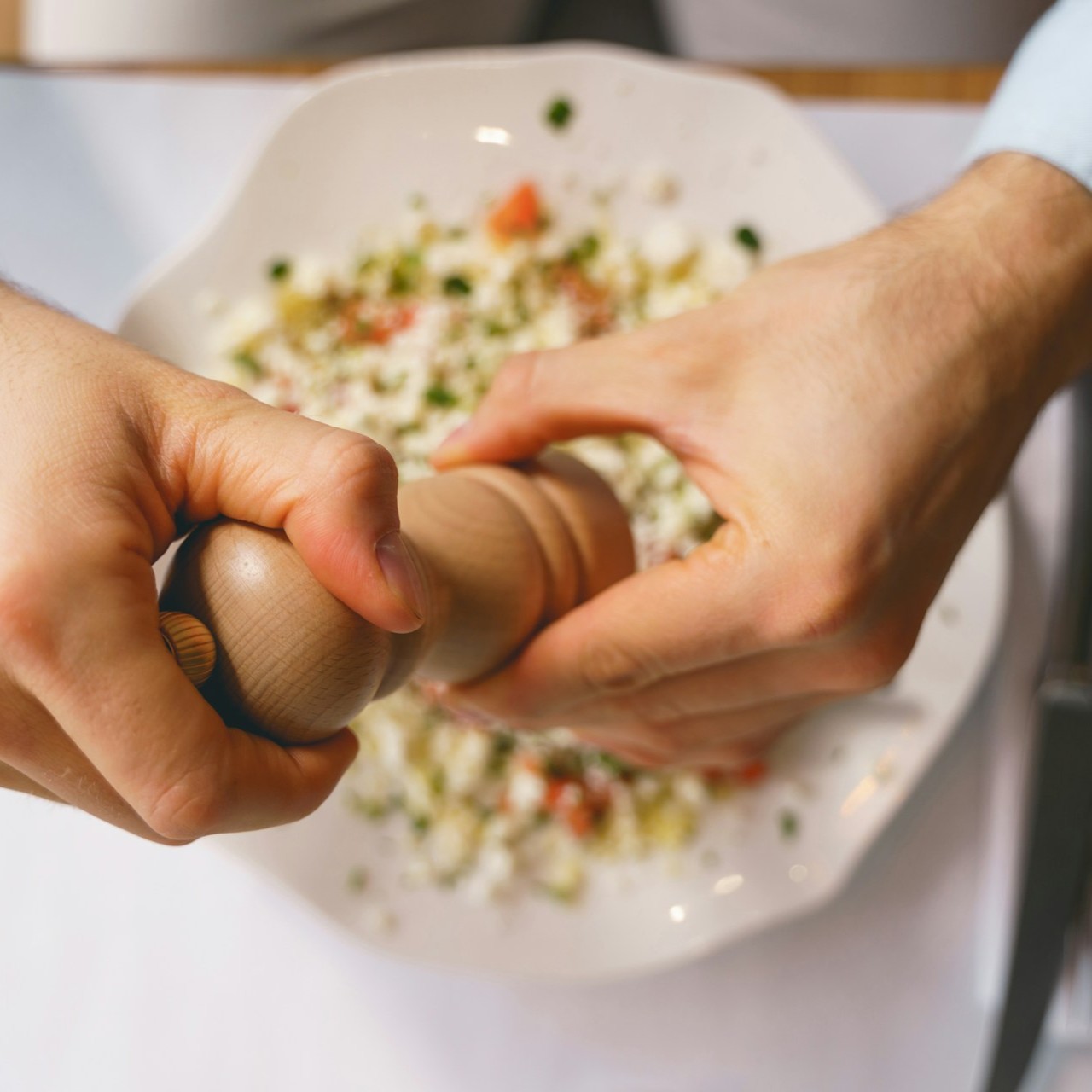 Grinding Pepper Over Salad Person grinds pepper over a fresh salad in a white bowl