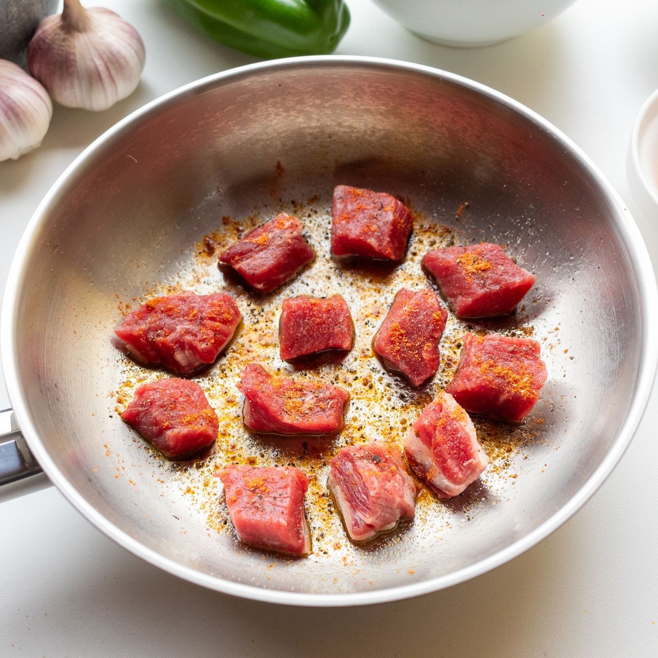 Seasoned Meat in Pan Cubed meat seasoned and cooking in a stainless steel pan