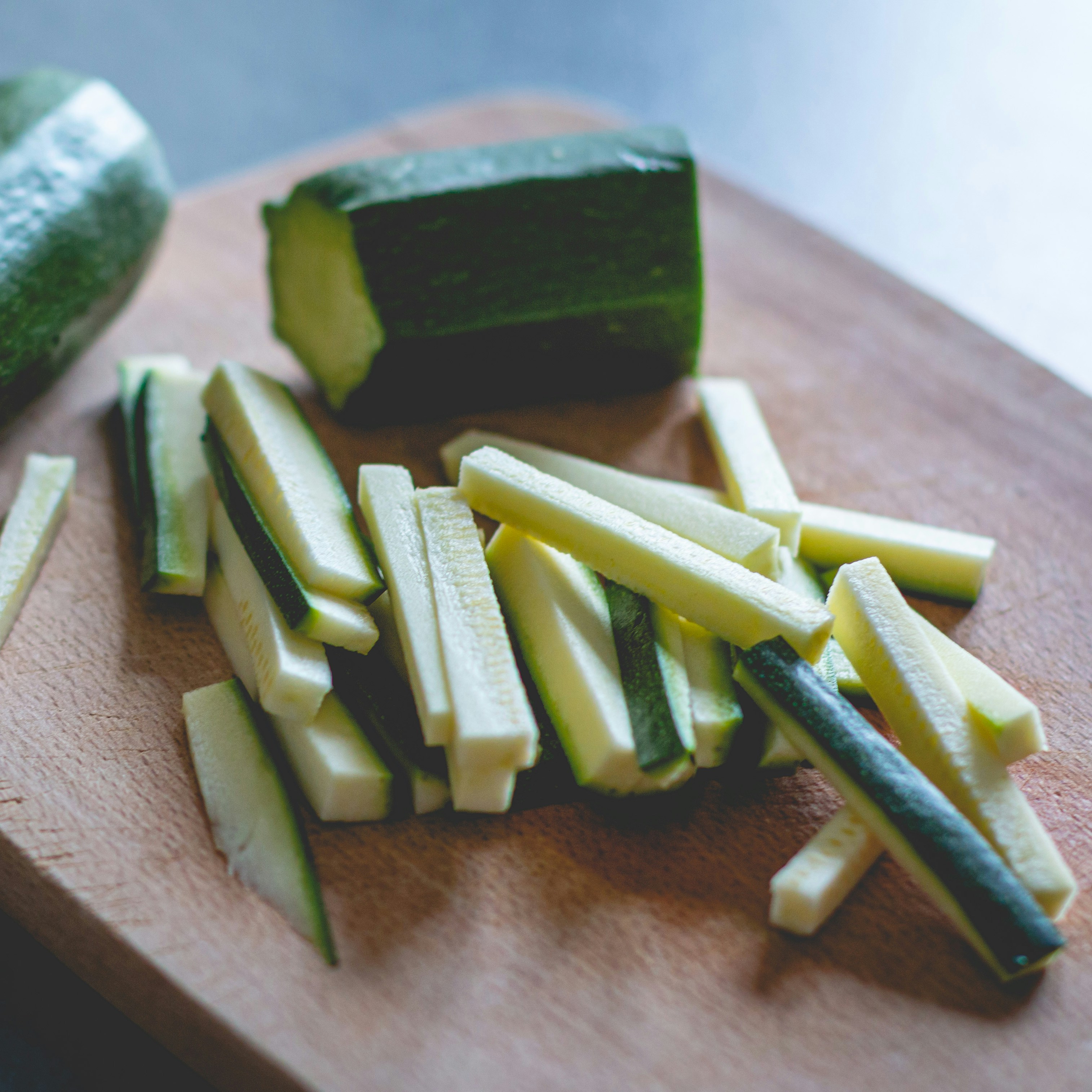 Zucchini Sticks on Cutting Board Sliced zucchini sticks are neatly arranged on a wooden cutting board