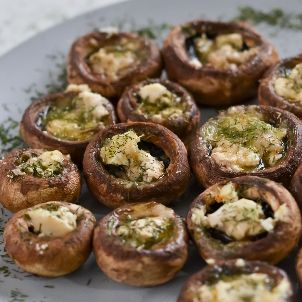 Stuffed mushrooms with herbs and cheese on a plate.