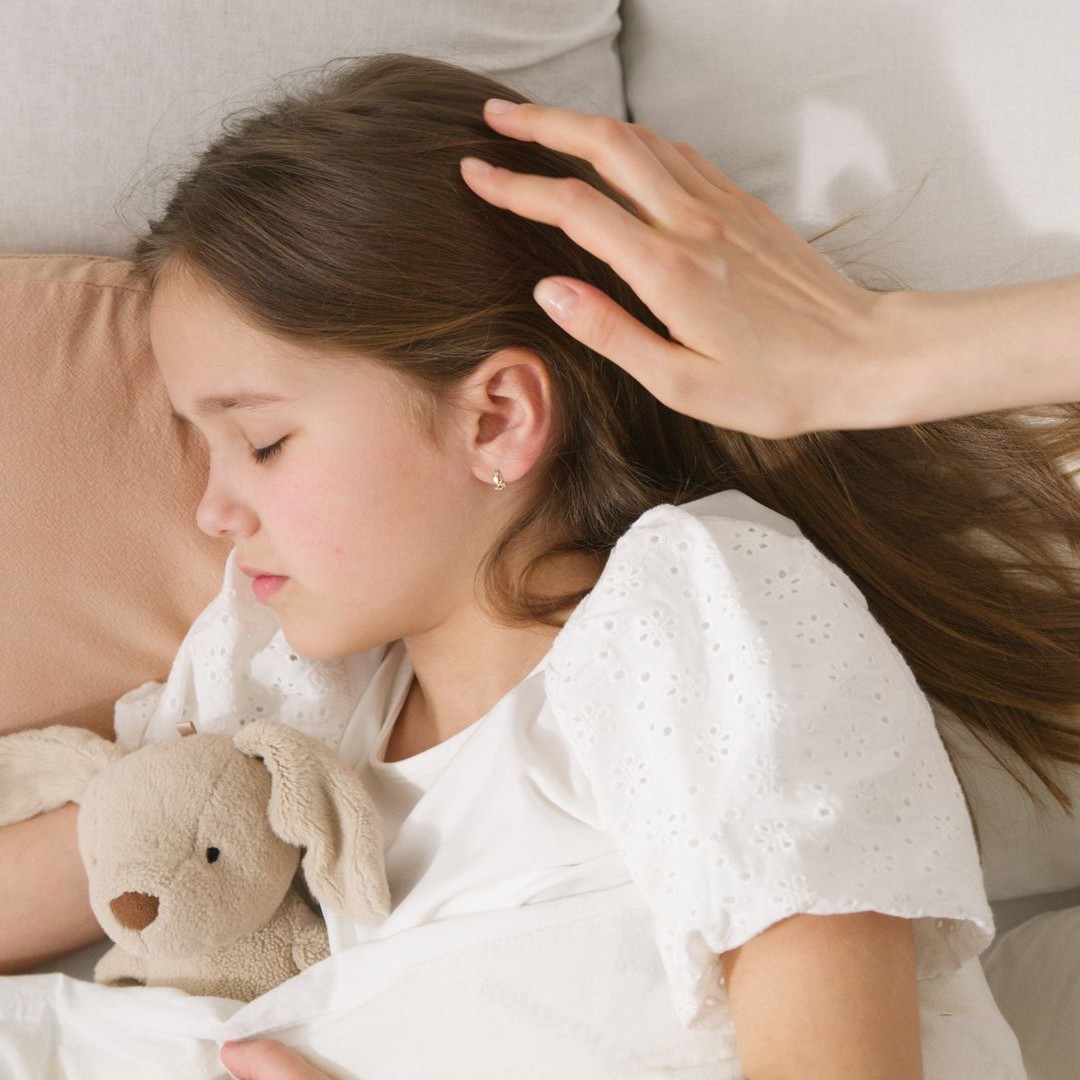 Child Sleeping Peacefully A child sleeps peacefully with a stuffed toy while a hand gently caresses her head.